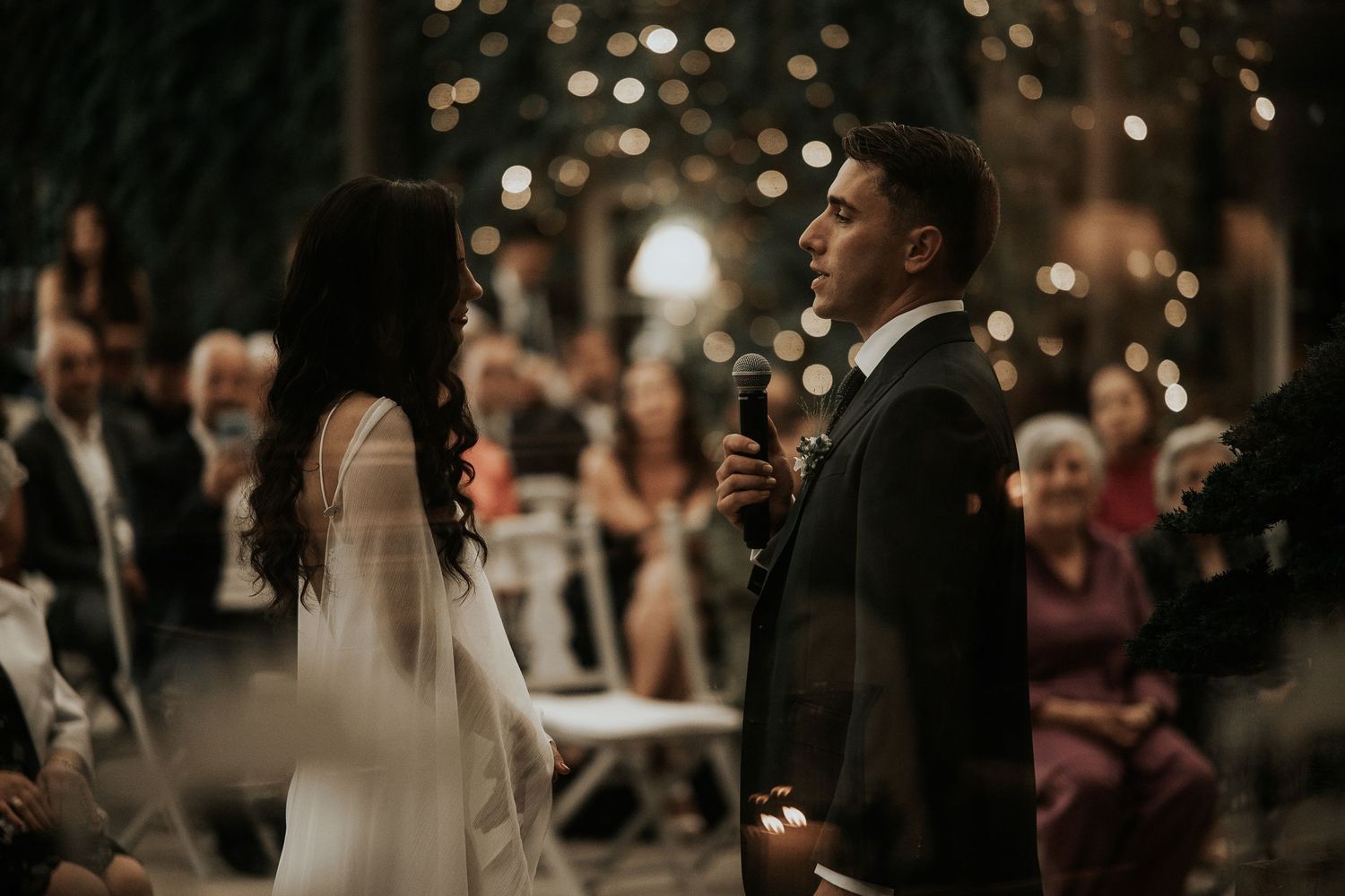A couple shares a romantic moment during their wedding ceremony while guests look on in the background.