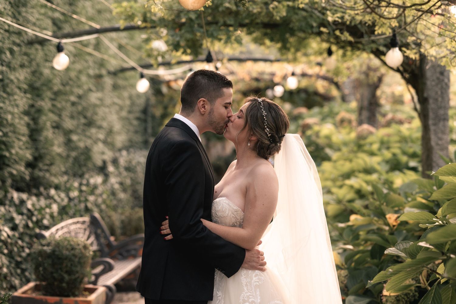 A romantic wedding couple shares intimate moments in a lush garden setting during their outdoor photo session.