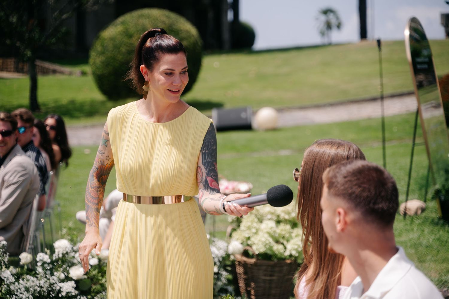 Wedding guests in yellow and formal attire gather outdoors on a sunny day for a celebration.