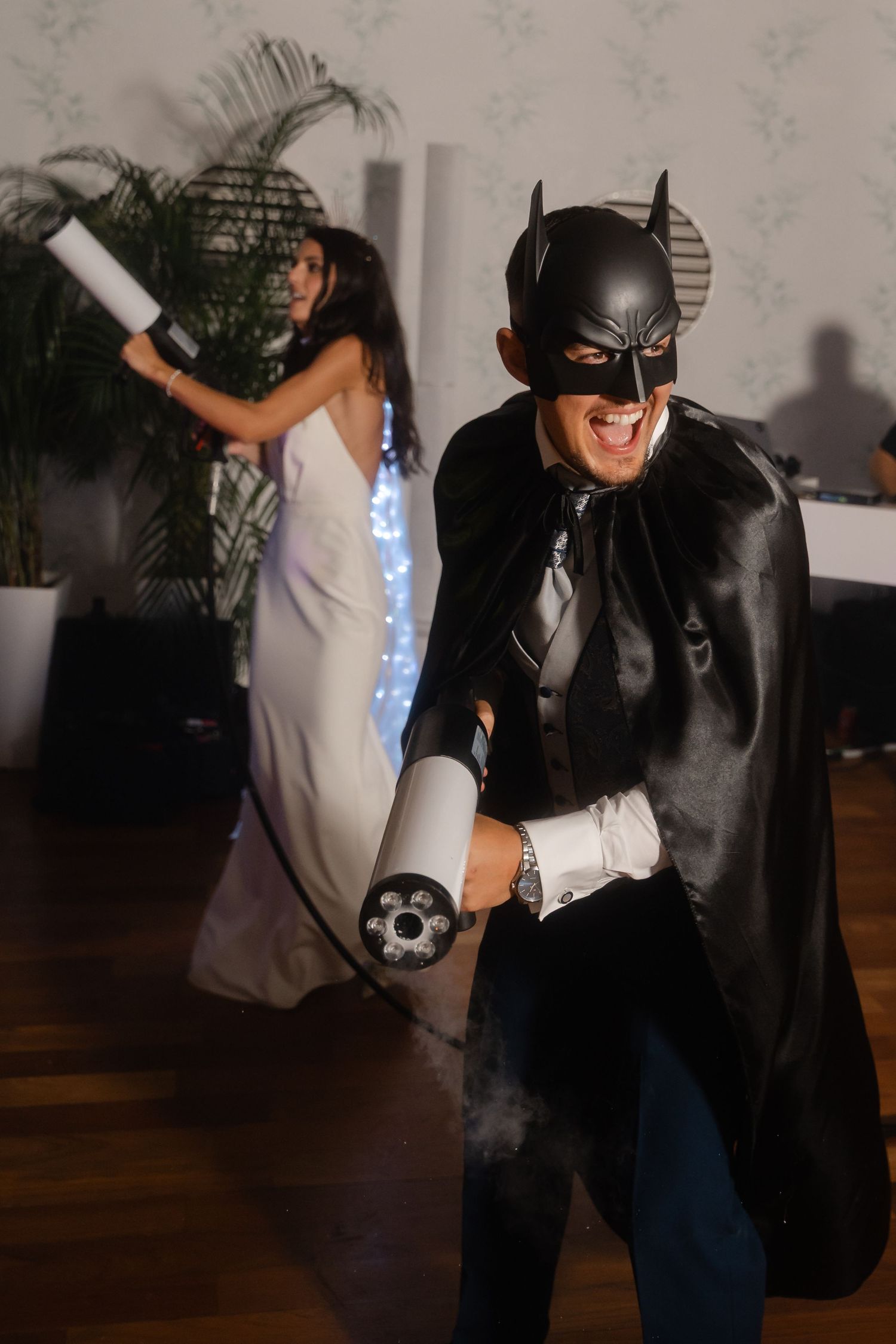 Person wearing a Batman costume interacts playfully in a casual indoor setting.