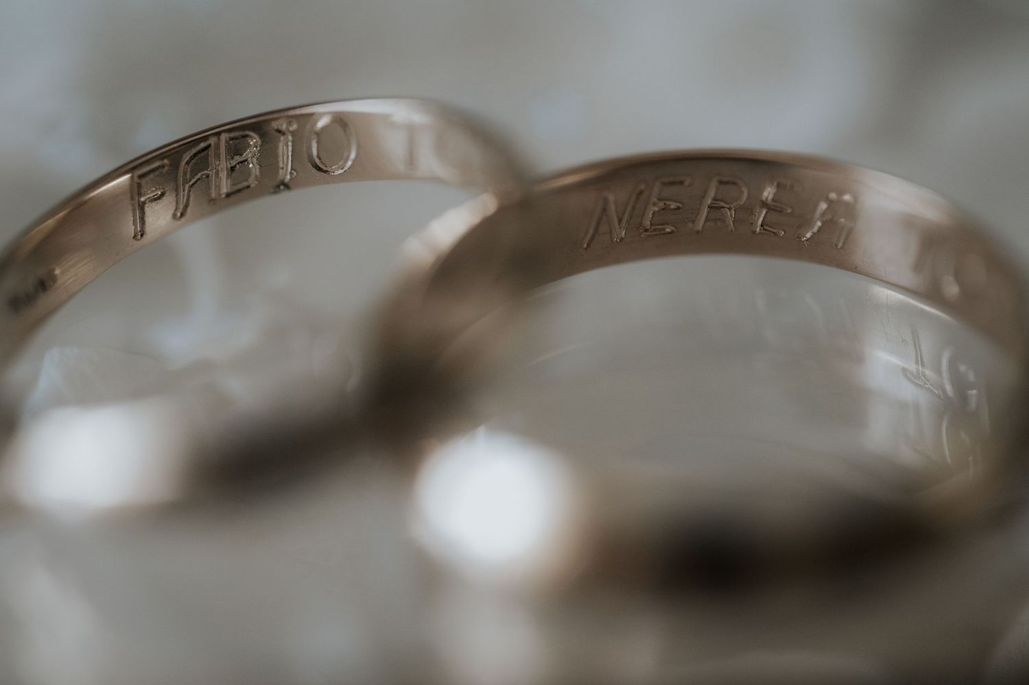 Close-up macro shot of two wedding rings with engraved text showing blurred bokeh background.