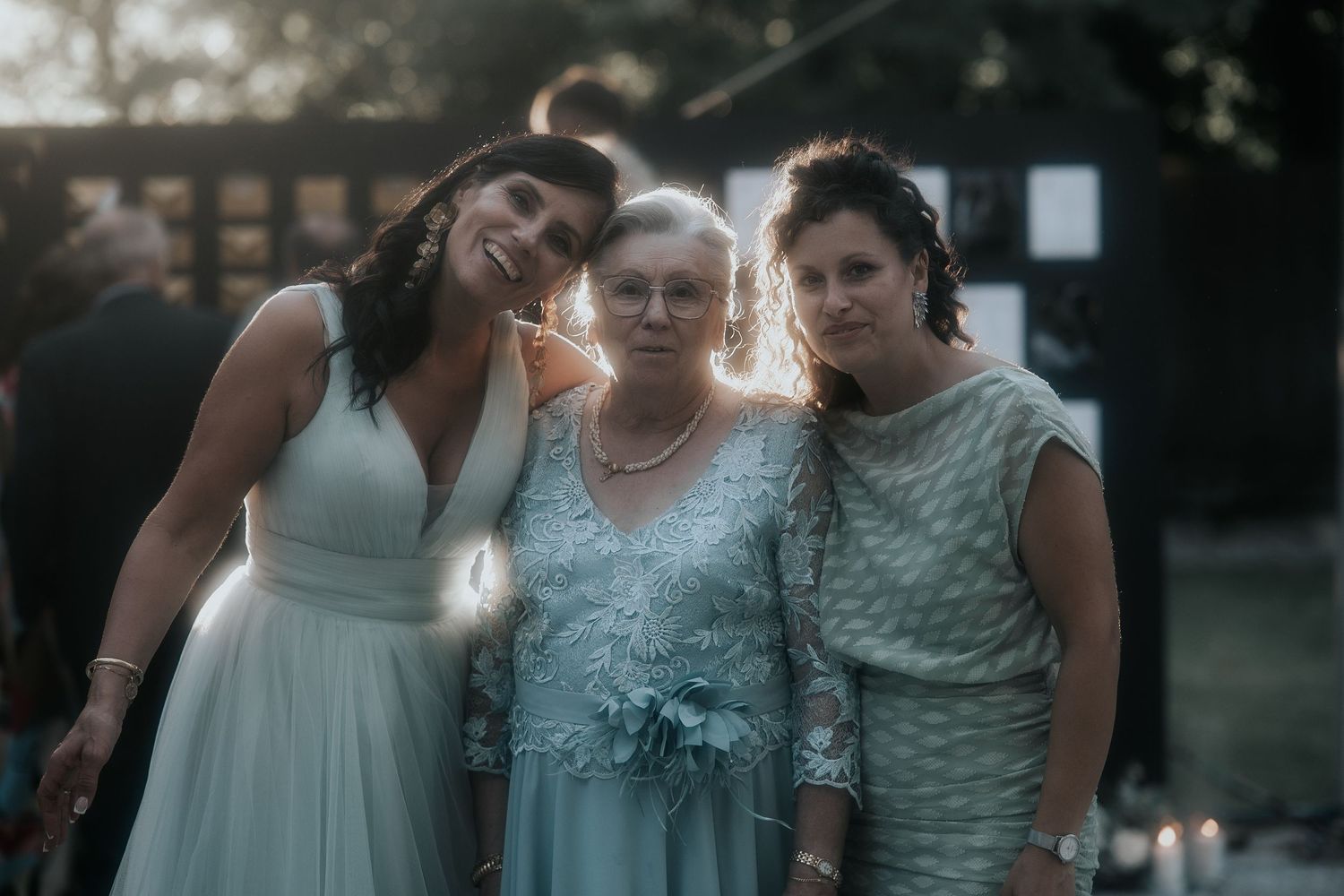 A group in light blue and white formal attire stands together during an outdoor evening celebration.