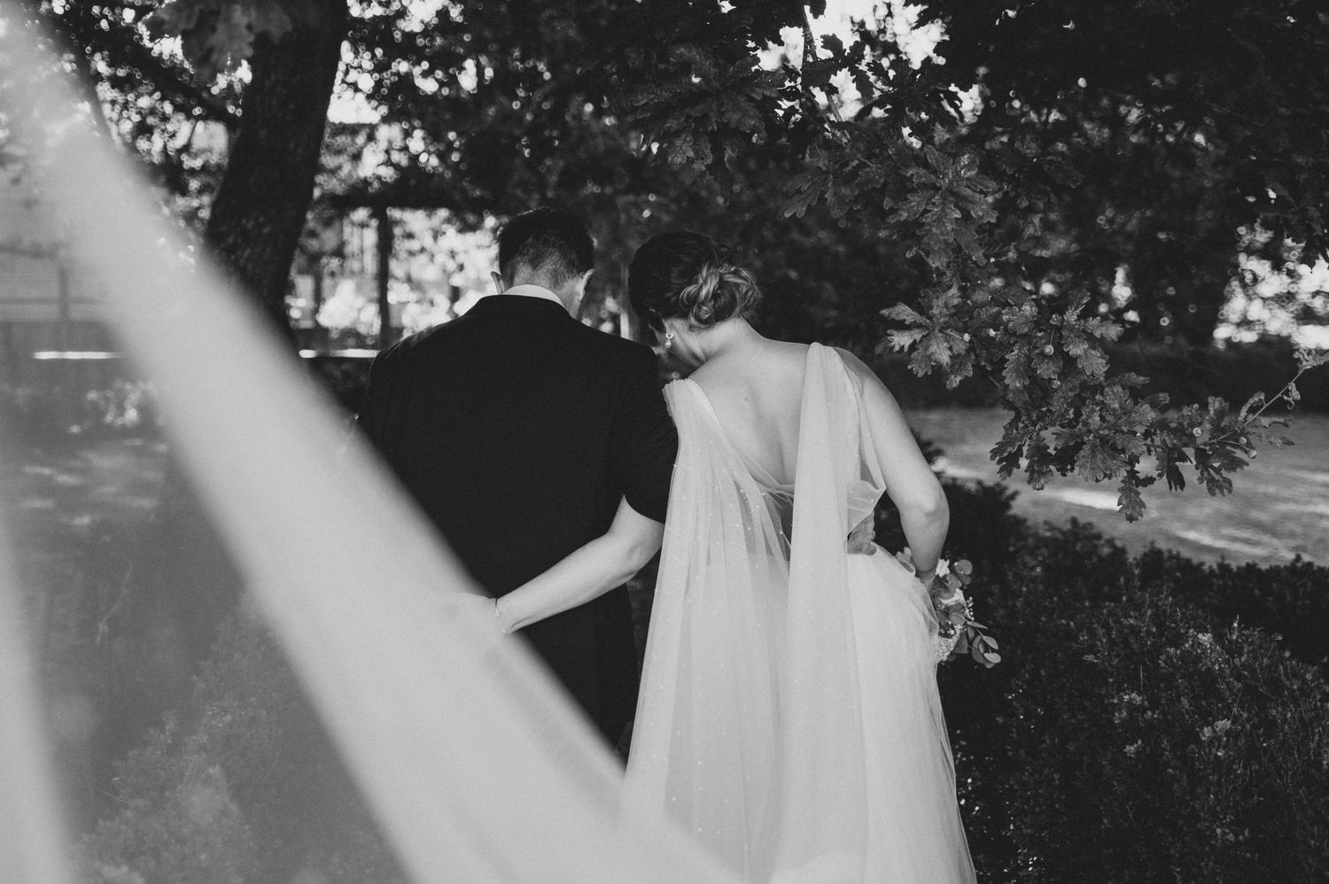 Black and white wedding photo series showing romantic moments between a couple in an outdoor garden setting.