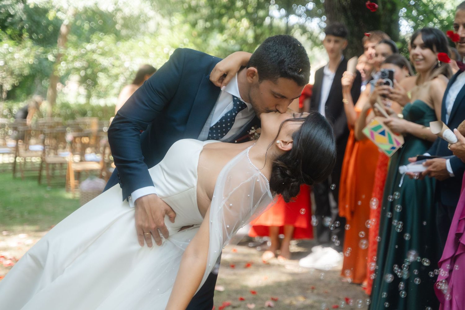 Wedding celebration in outdoor garden setting with guests in colorful attire.