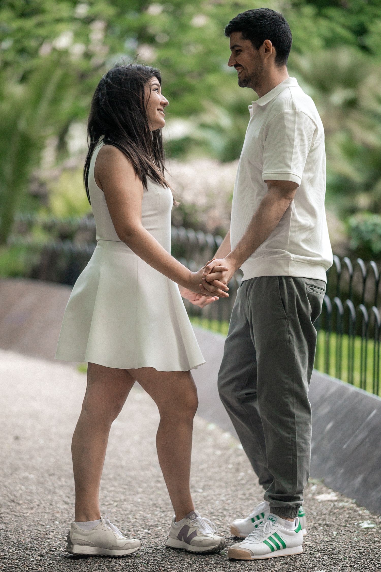 Close-up shots of a couple's feet in white shoes standing together on a paved pathway.