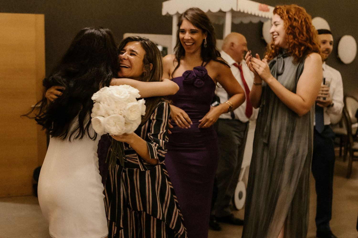 People dancing together at a social event in a dimly lit venue with warm lighting.