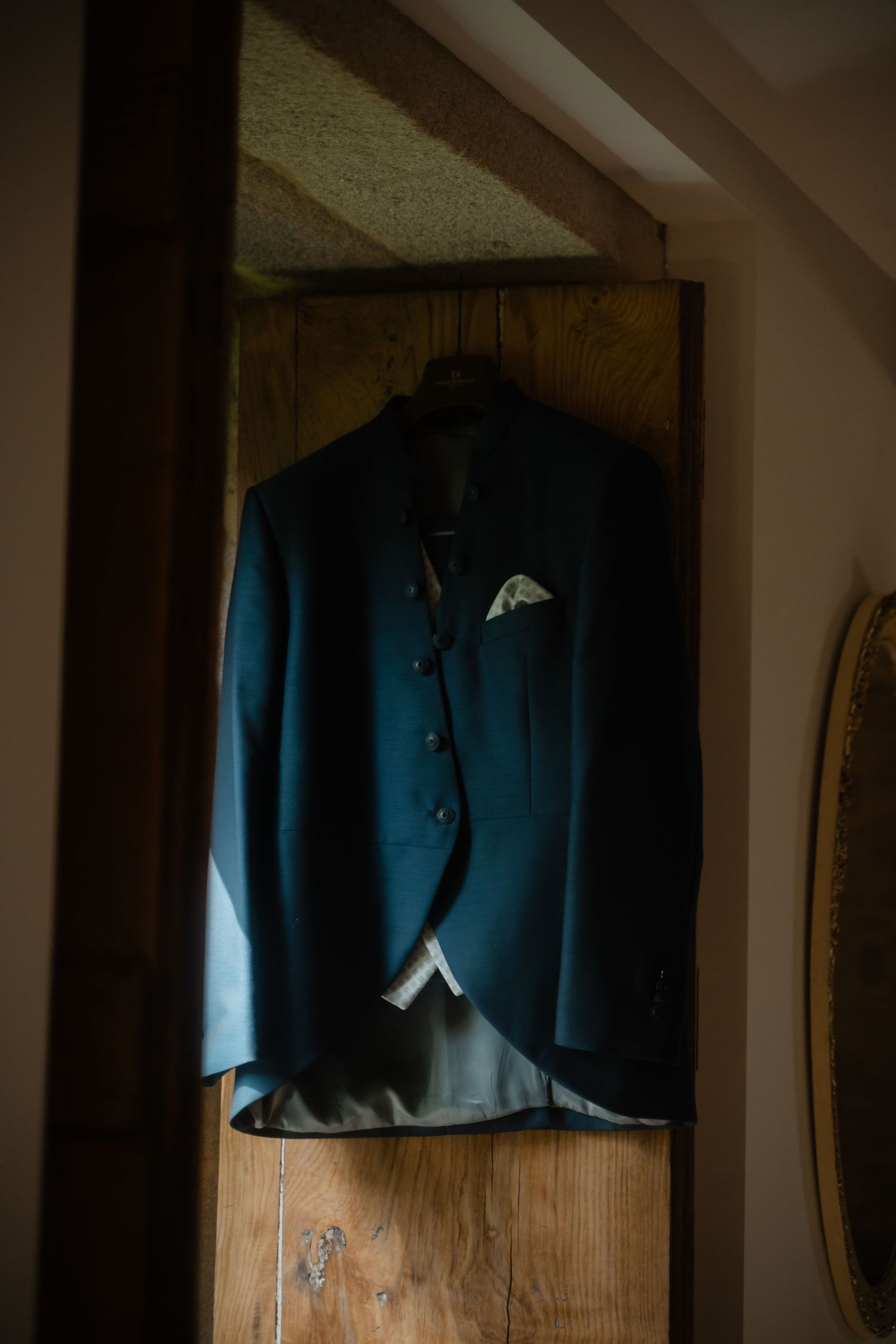 A series of navy blue suit jackets hanging on wooden hangers in a closet.