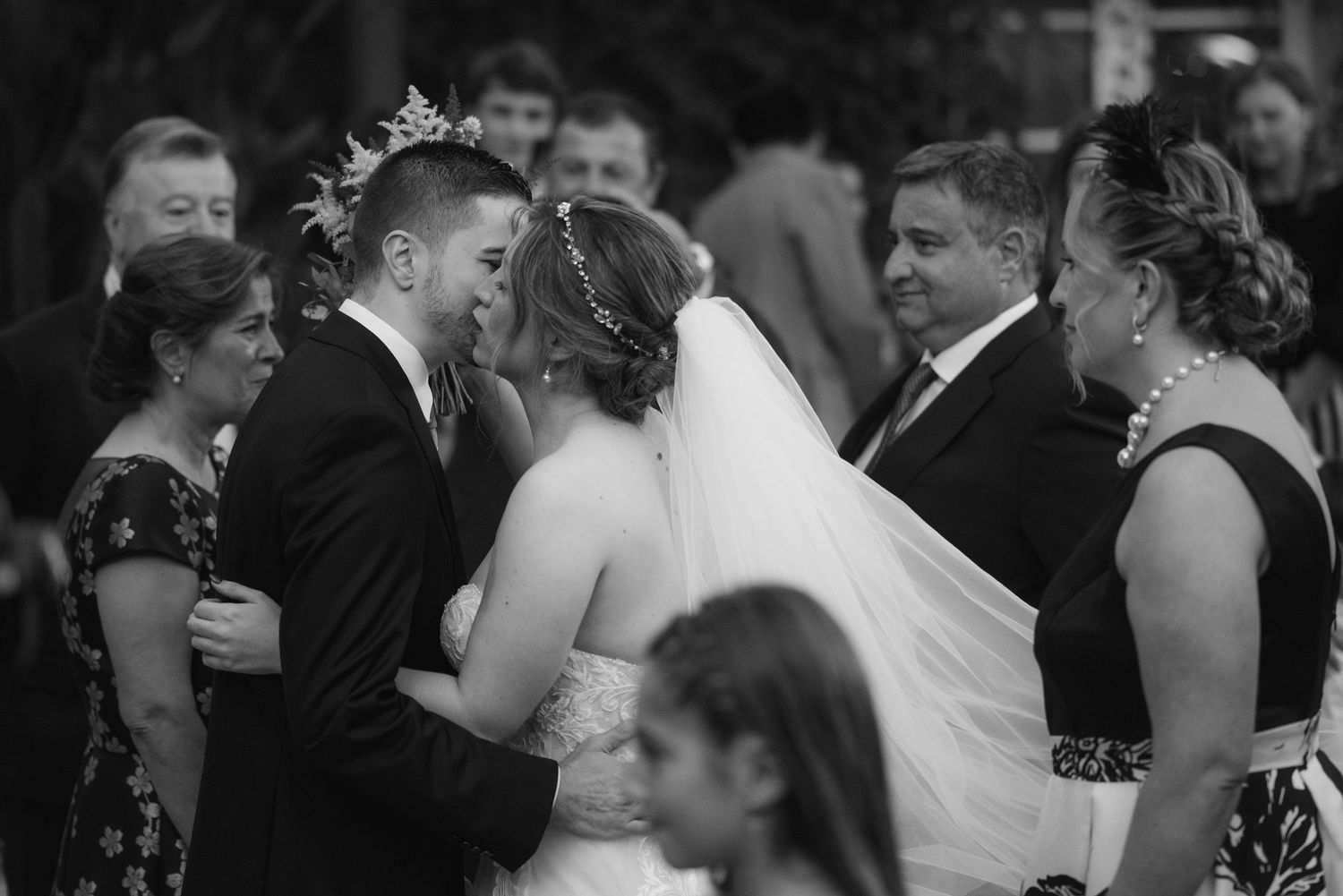 Wedding guests dancing and celebrating together at an indoor reception with festive lighting.