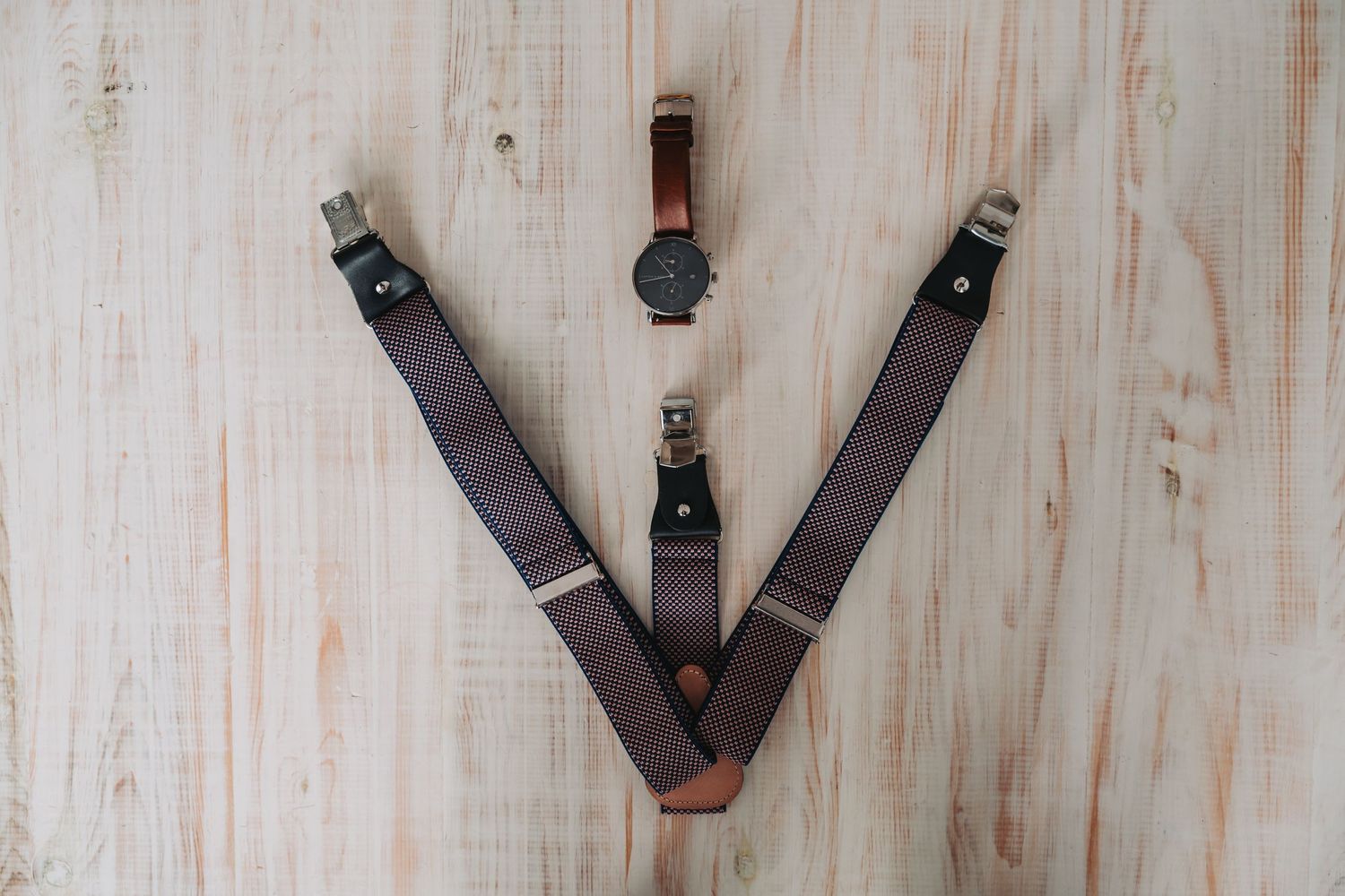 A row of brown leather razor strops mounted on a light-colored wooden wall.