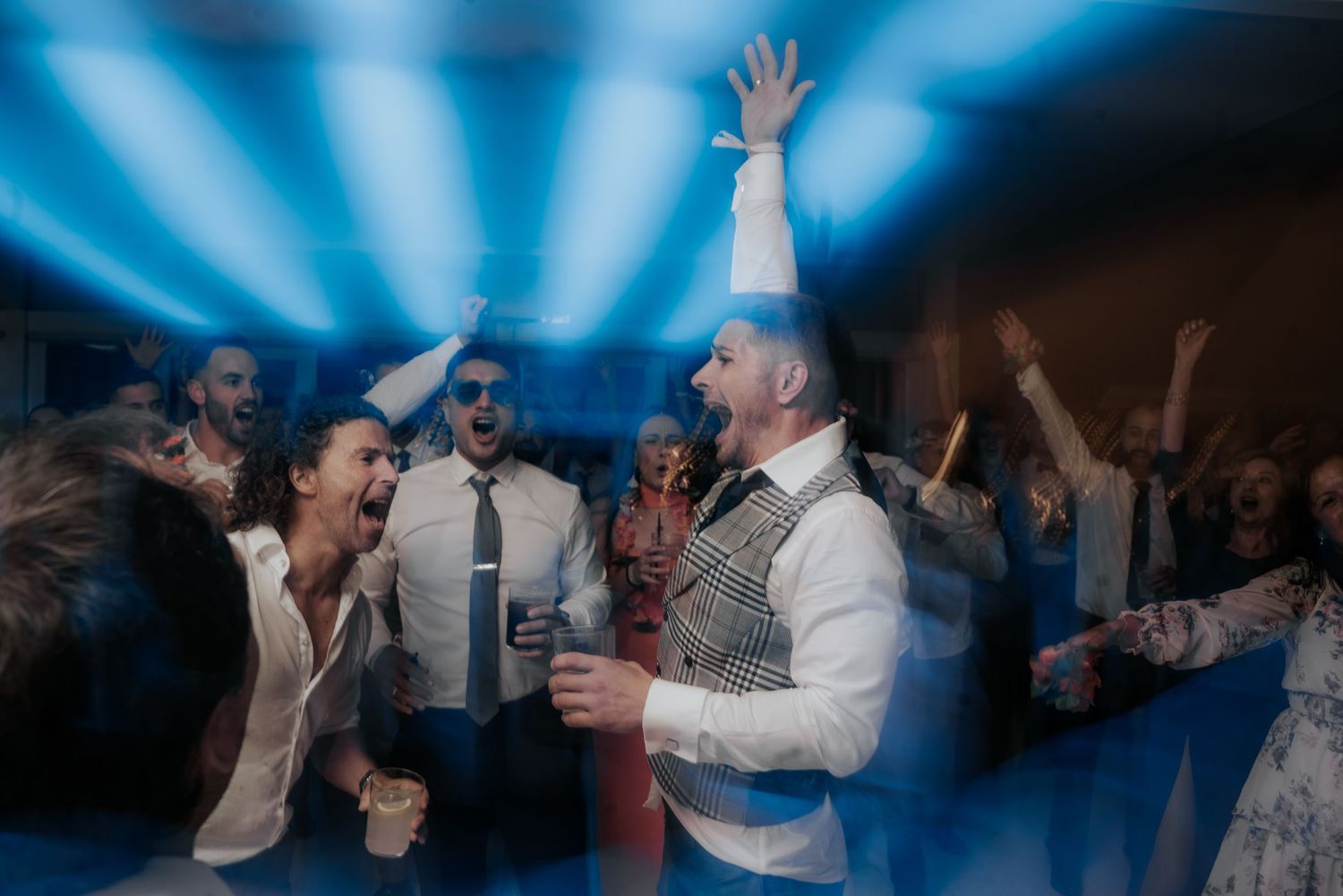 Partygoers enjoying themselves under dramatic blue lighting at an evening celebration.