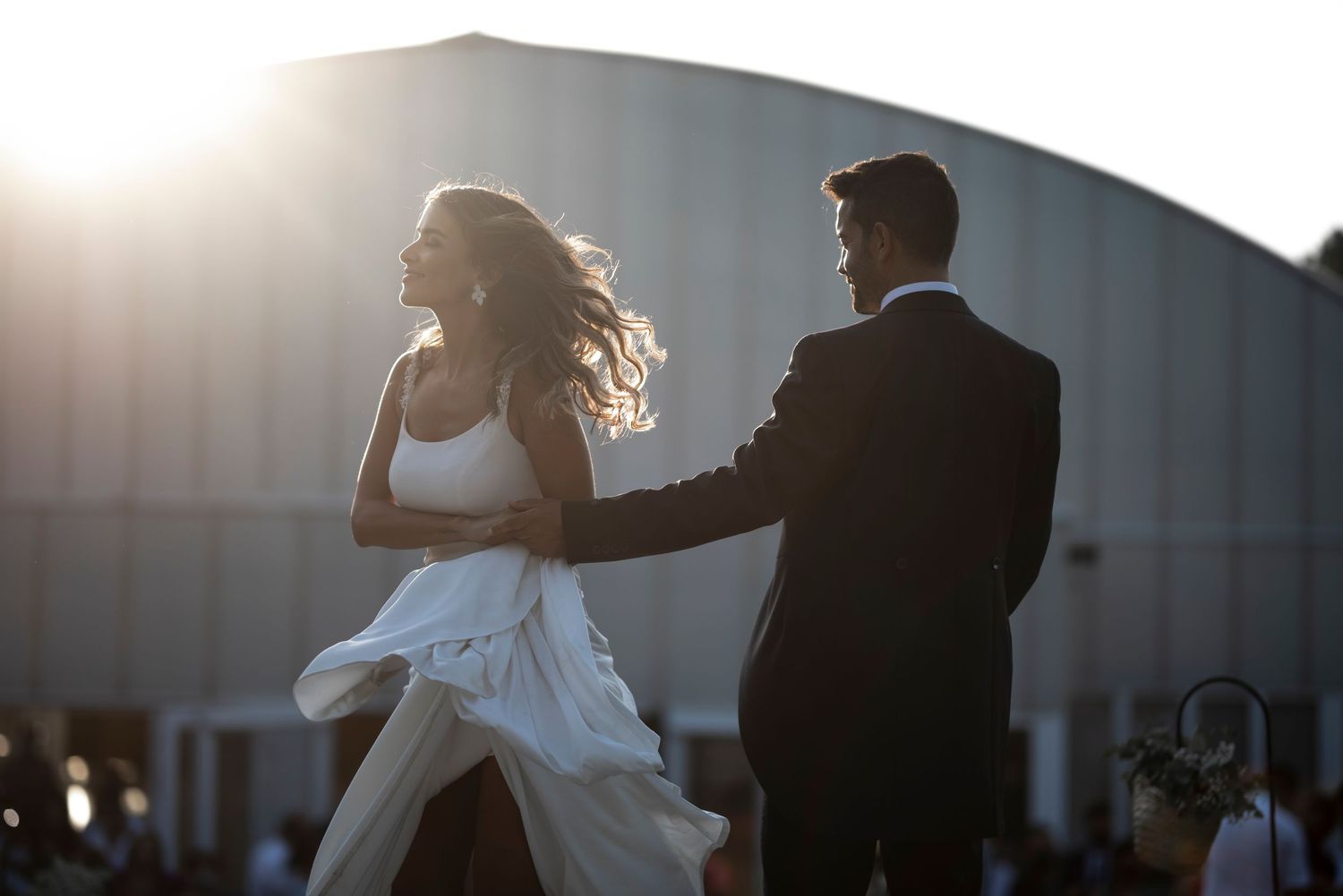 Silhouetted couple dancing together during sunset at their wedding reception.