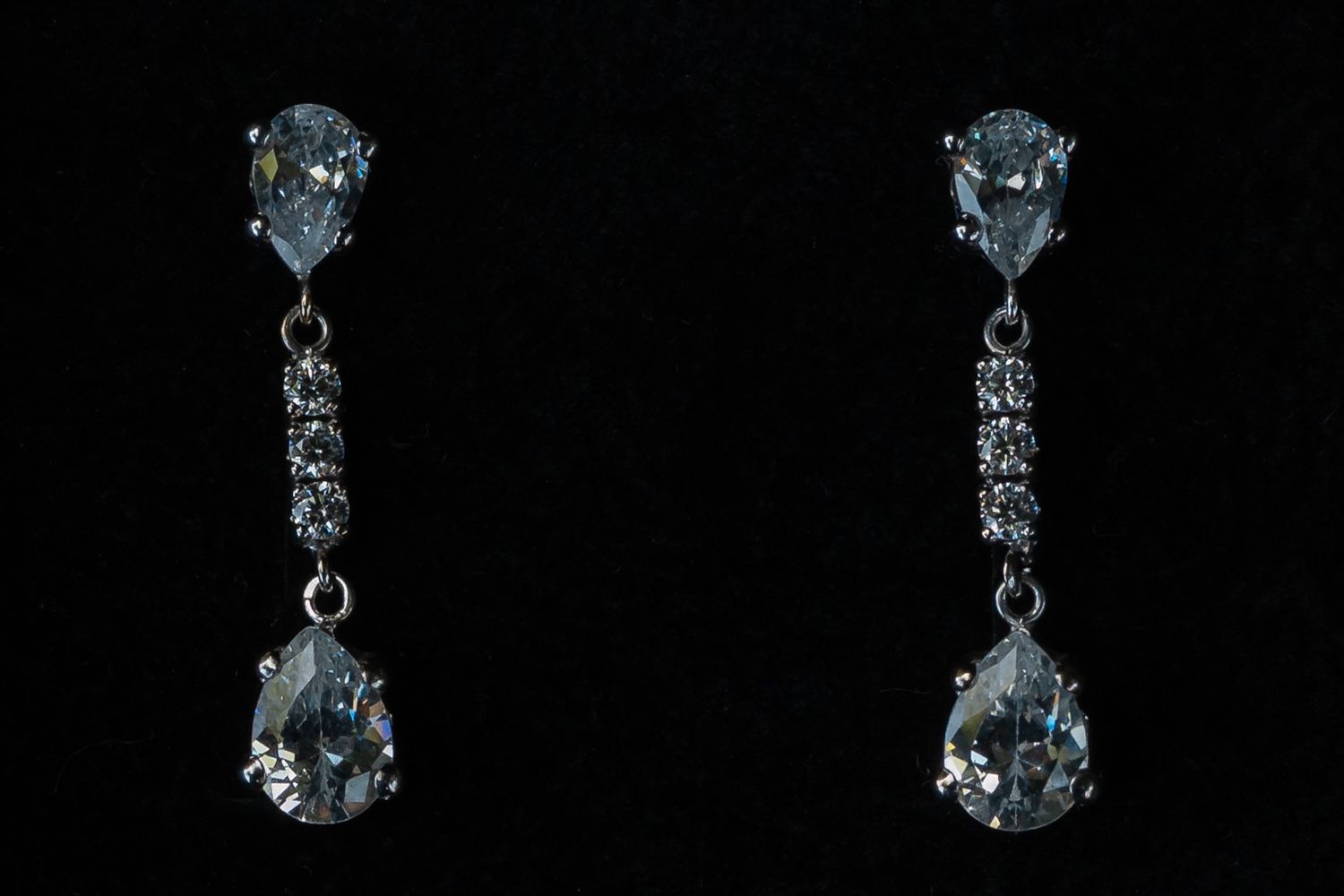 Elegant crystal teardrop earrings sparkle against a black background in a jewelry product photo.