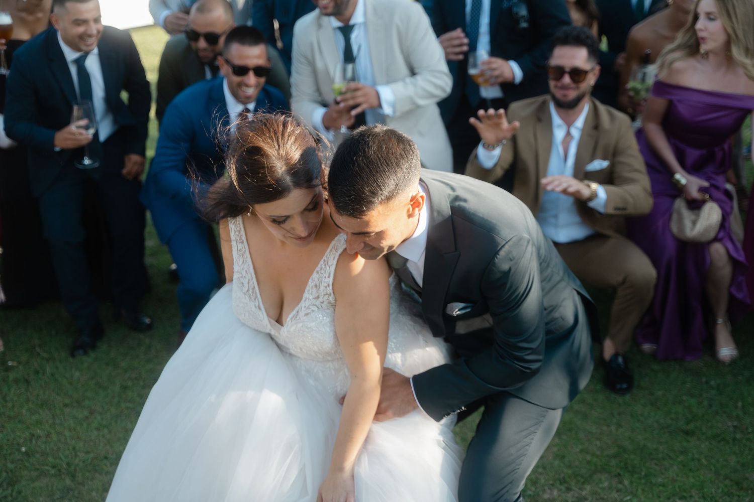 Couple sharing a romantic moment during their outdoor wedding ceremony as guests look on.