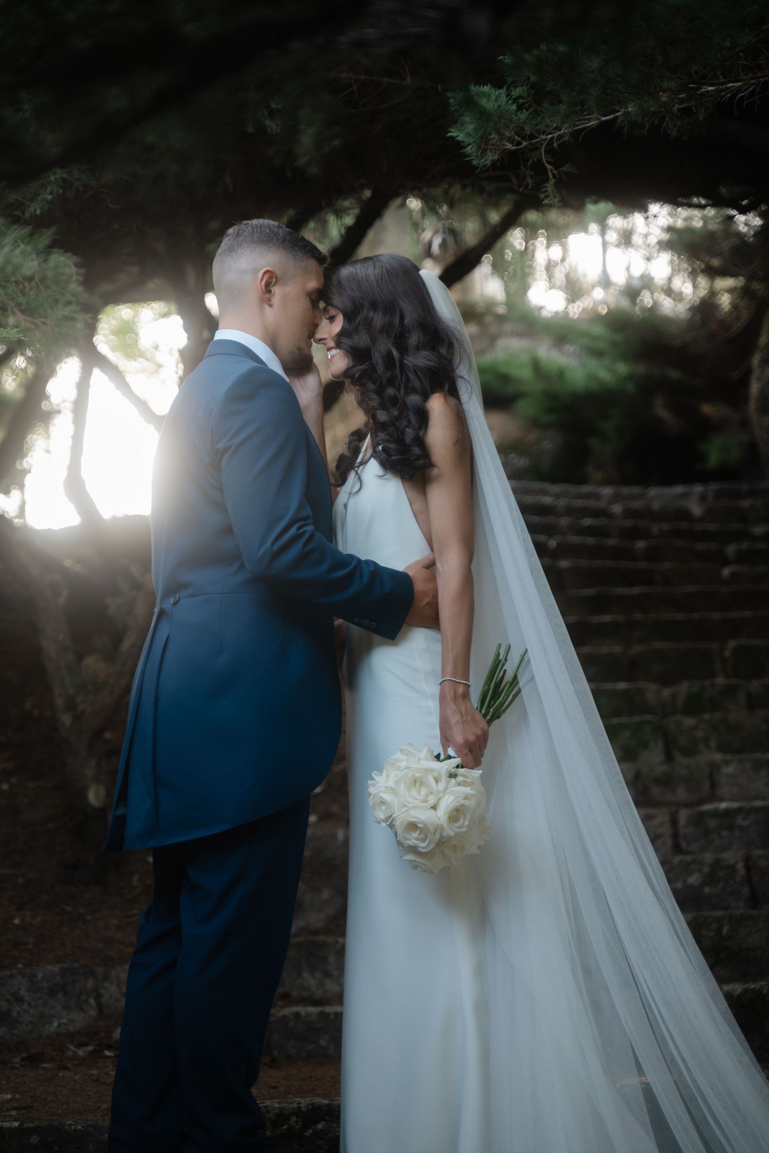 A romantic wedding moment captured in a sequence showing the couple sharing a tender kiss under trees.