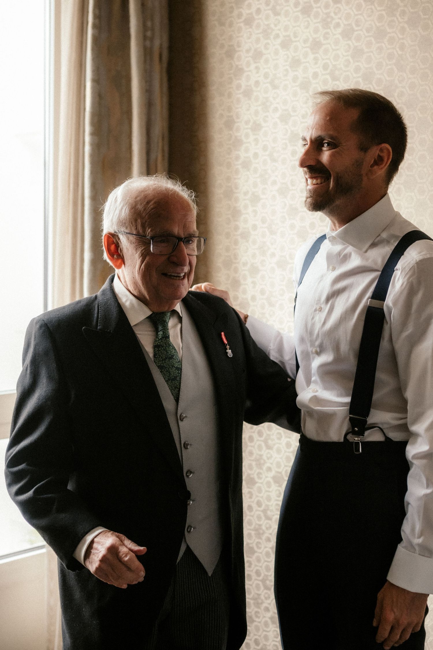 Three candid moments of men in formal attire sharing laughter and conversation near a window.
