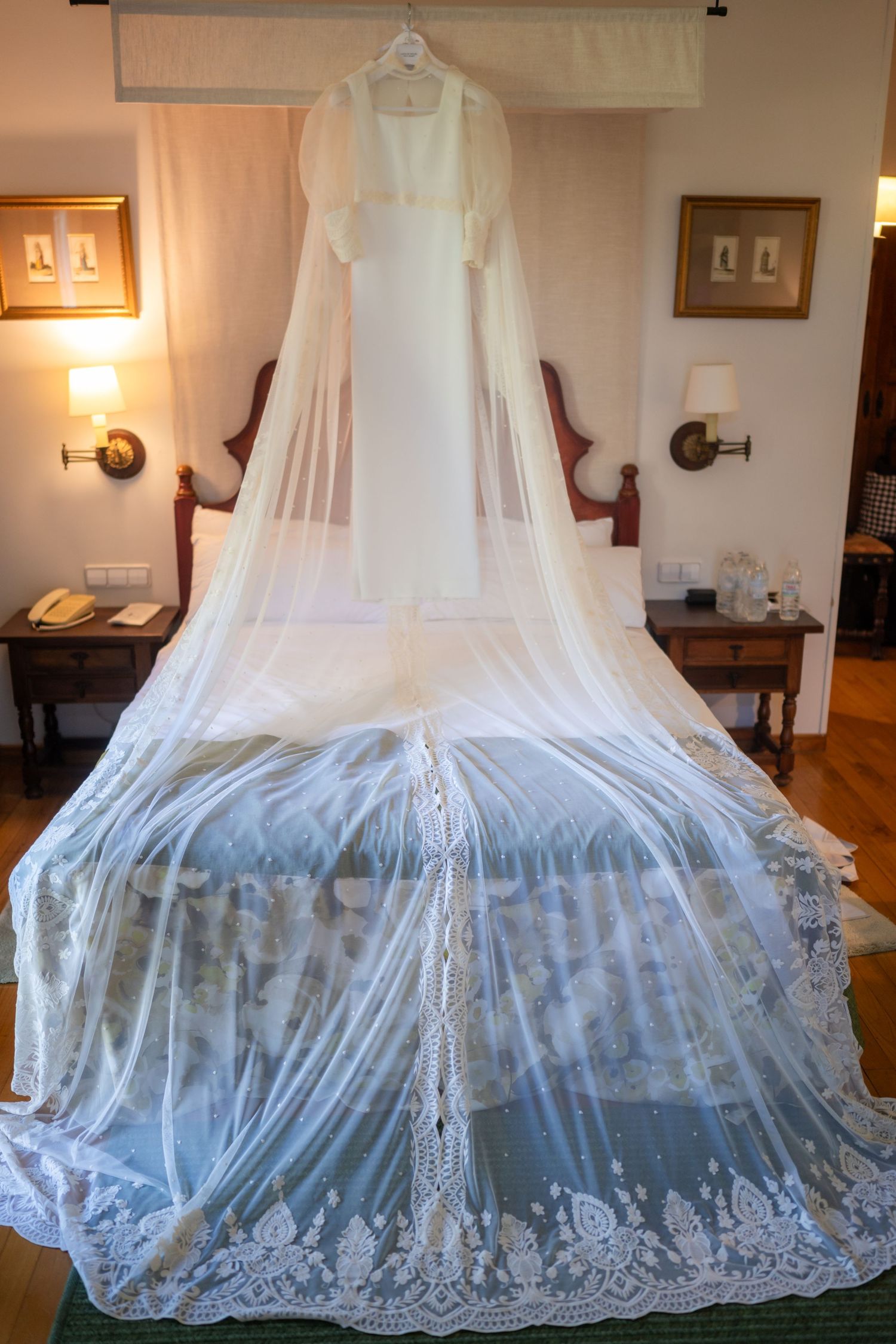 Elegant white lace canopy bed netting with delicate embroidered details hangs gracefully in a warmly lit bedroom.
