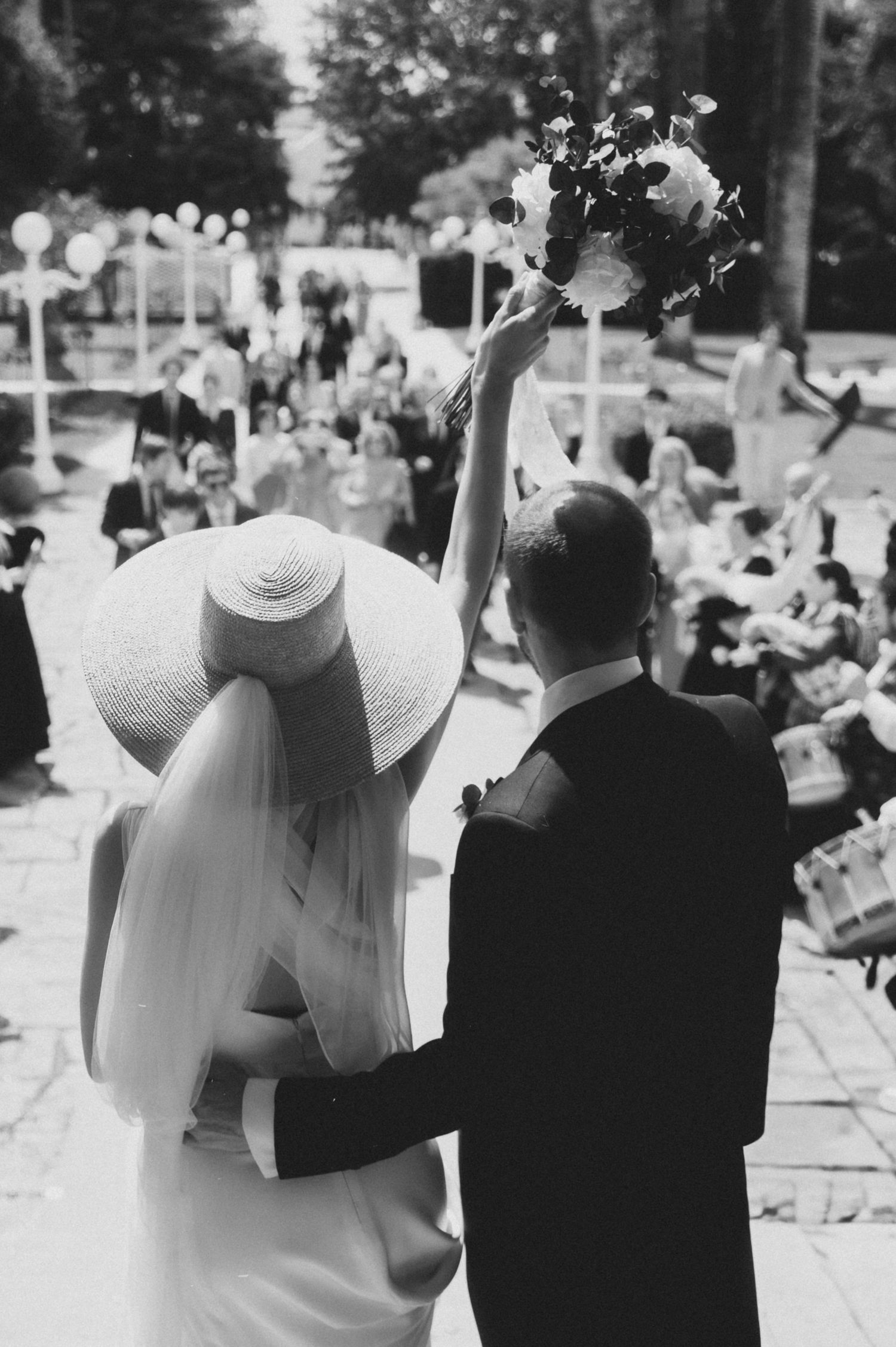 Wedding guests wave farewell to the couple during an outdoor summer celebration.