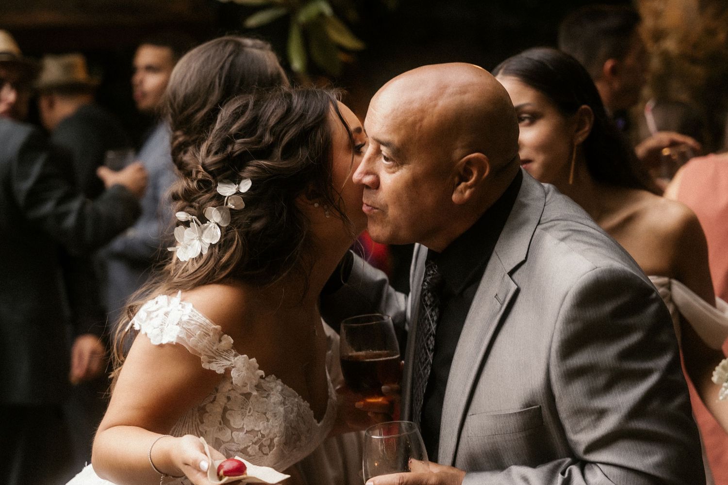 A couple shares an intimate dance moment at their wedding reception while guests look on in the background.