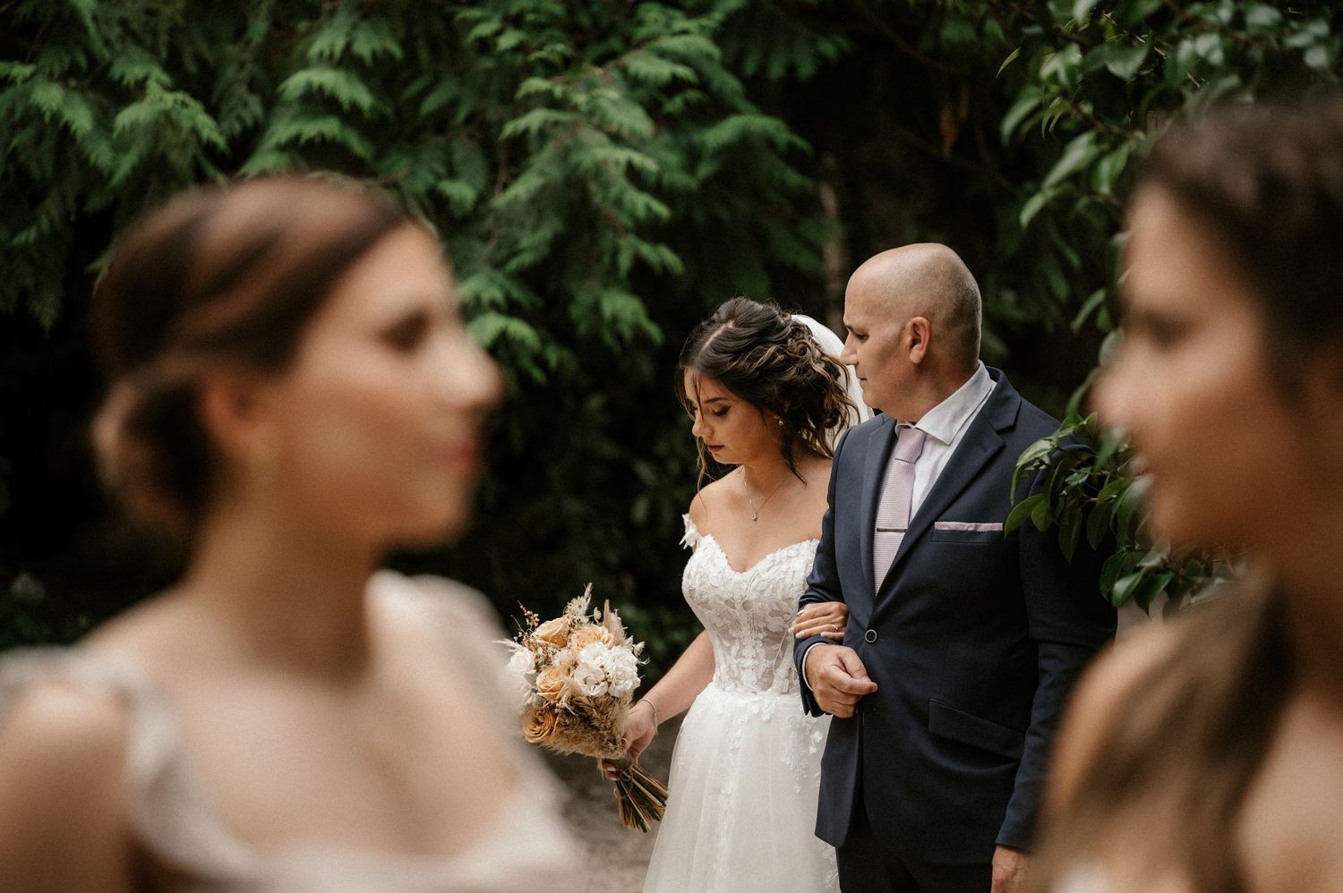 Wedding ceremony guests gather outdoors surrounded by lush greenery and natural scenery.
