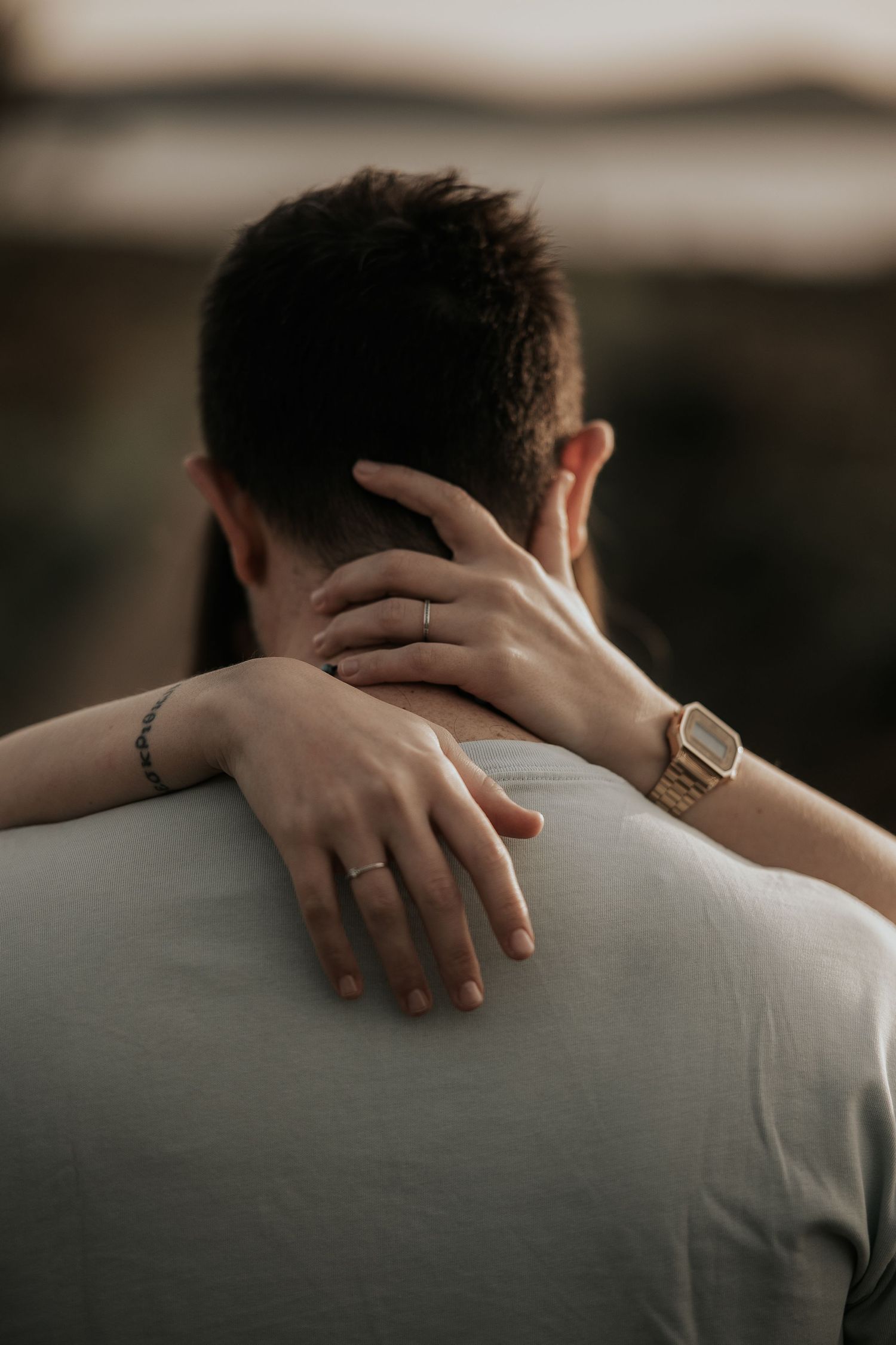 Close-up shots of hands embracing across shoulders showing rings and intimate connection.