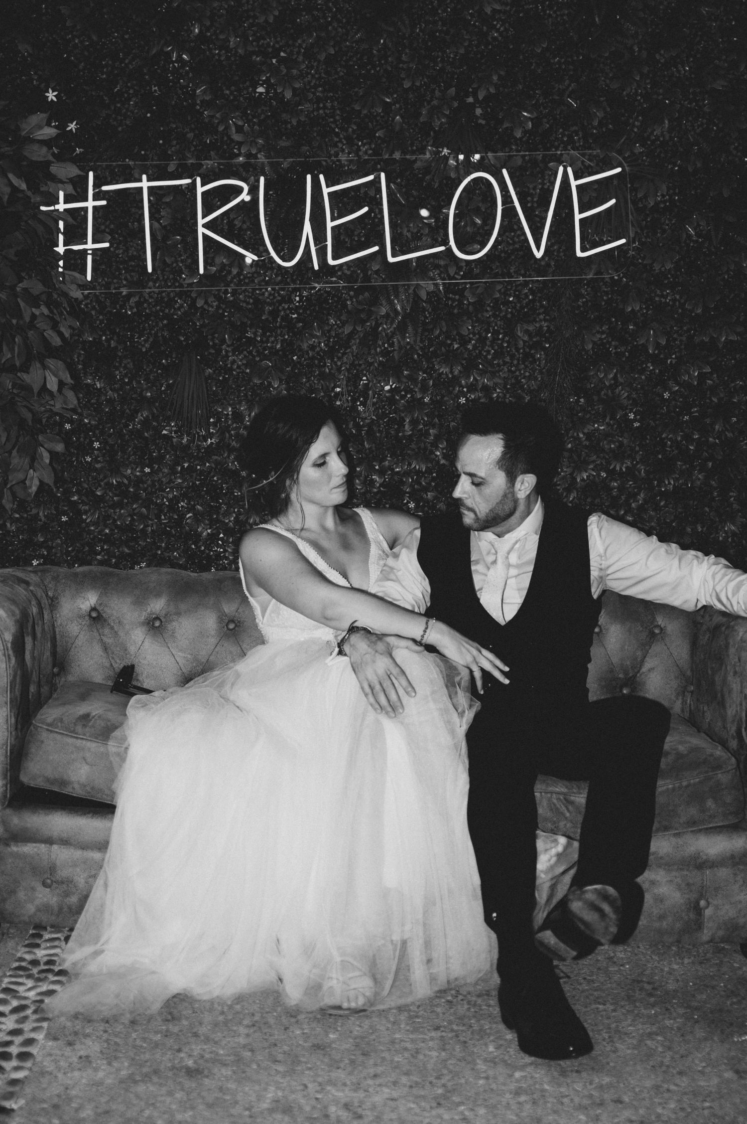 Black and white wedding photos show a bride in a white gown reclining in snow with hashtag true love written above.