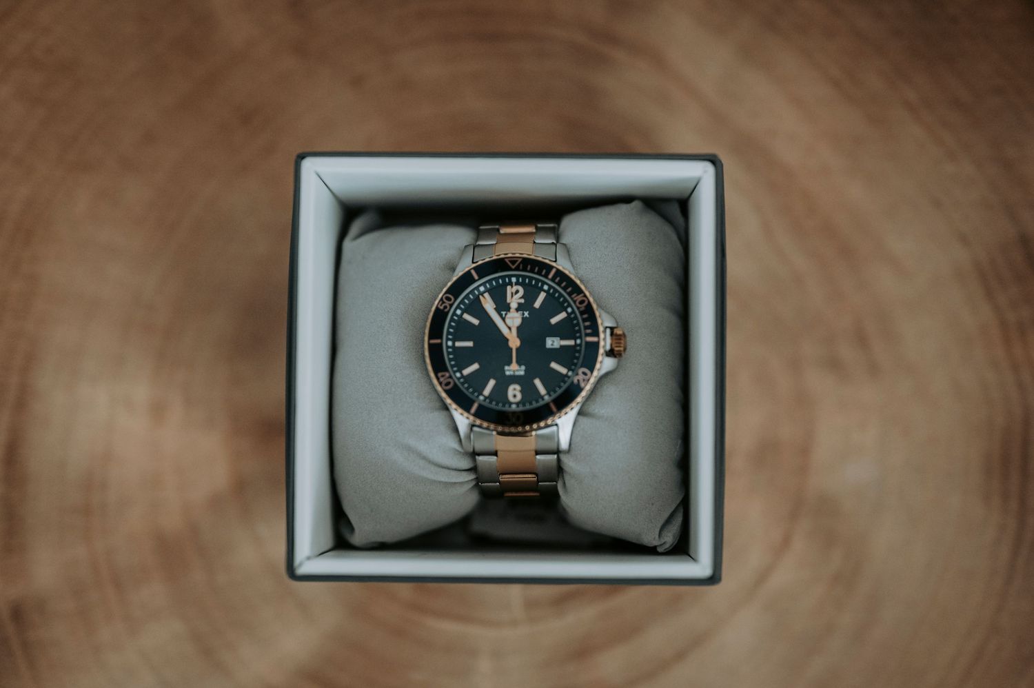 A series of luxury watches displayed in gray presentation boxes on a wooden surface.