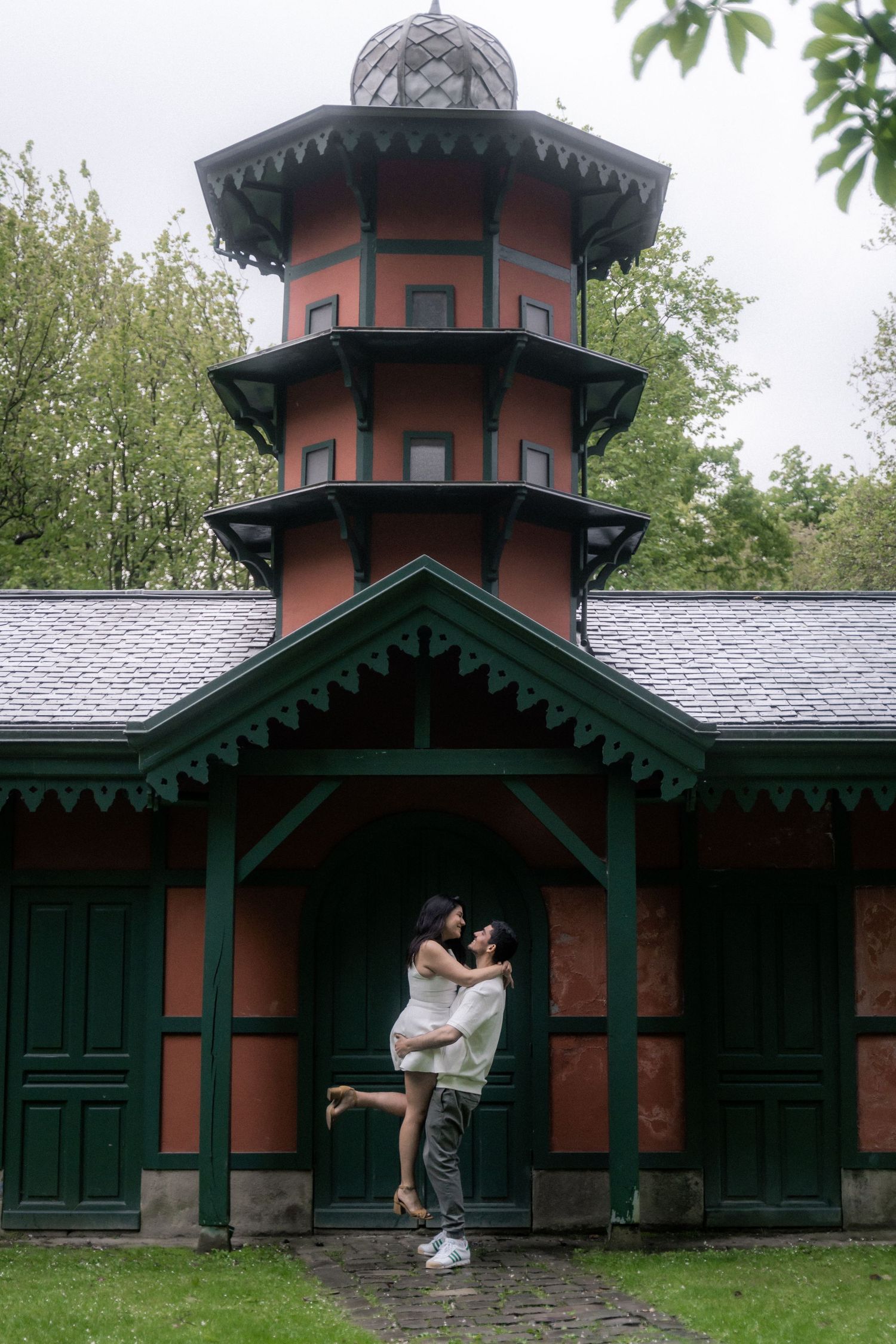 Historic Victorian-style building with orange and green trim surrounded by trees.