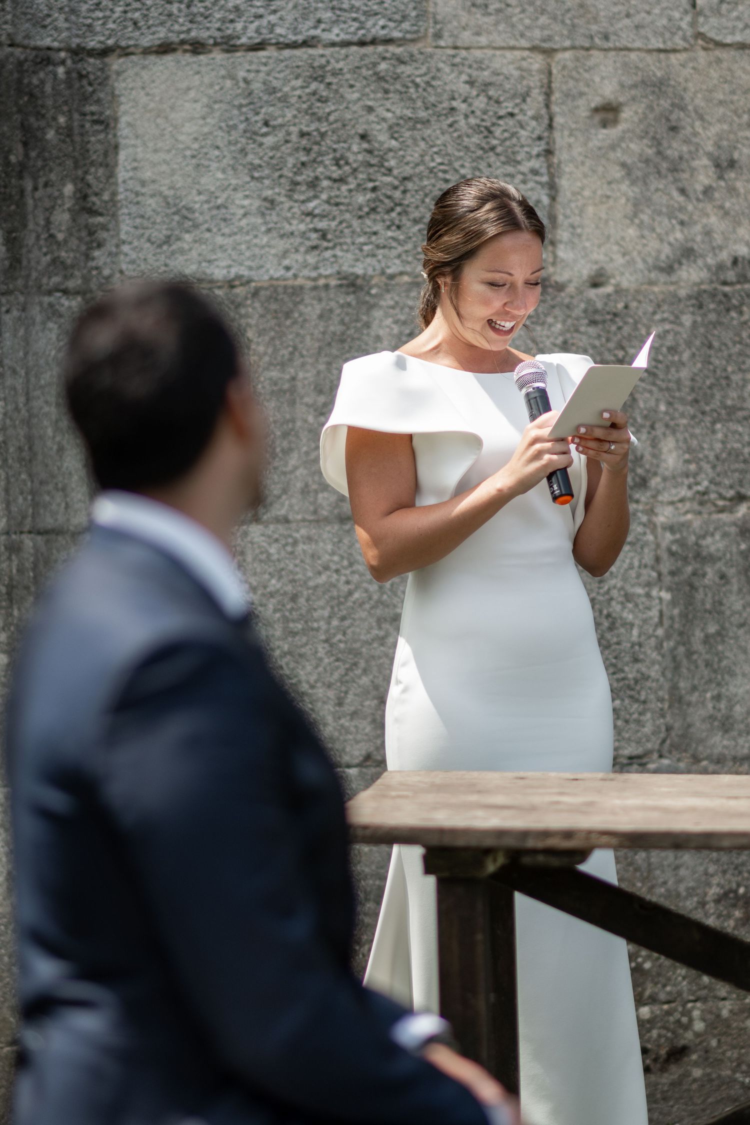 A couple shares a private moment during their wedding ceremony against a stone wall backdrop.