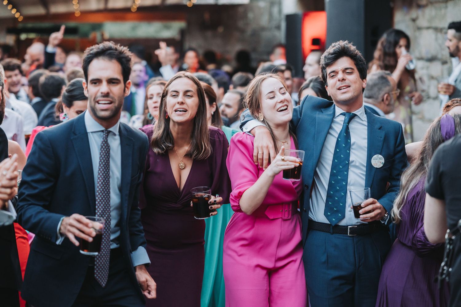 Wedding guests in formal attire enjoying themselves at an outdoor reception venue.