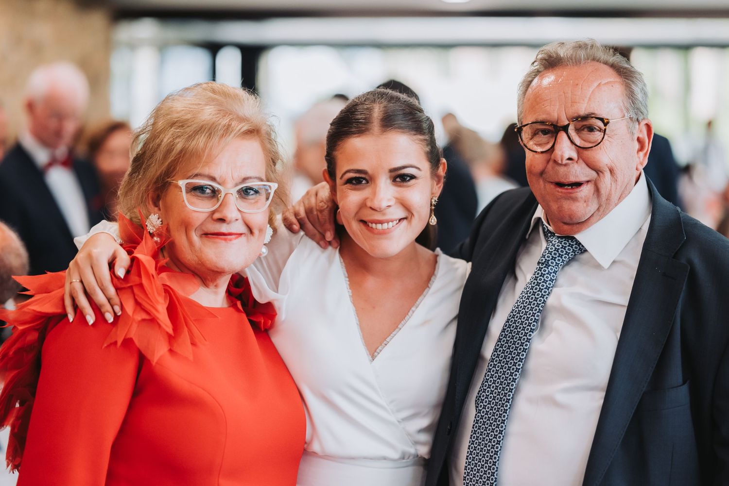 A group of wedding guests pose together in a joyful candid moment at a celebration.