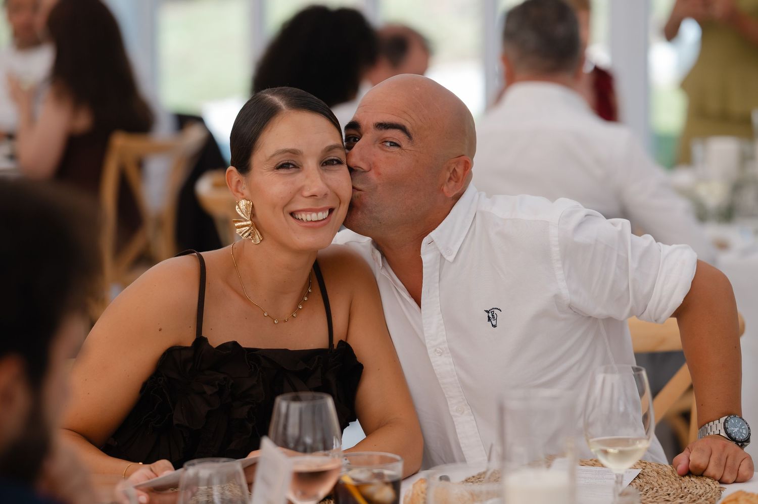 Wedding guests share laughter and conversation at an elegant reception dinner table.