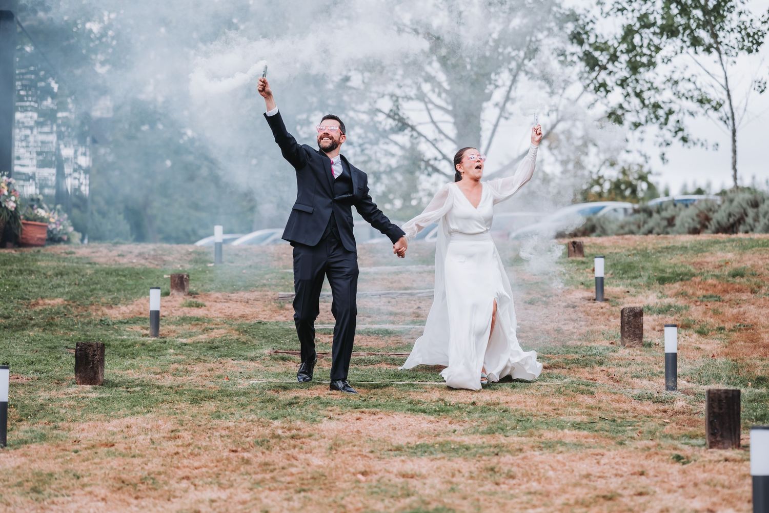 A newlywed couple dances and celebrates joyfully across a misty outdoor setting in a series of candid moments.
