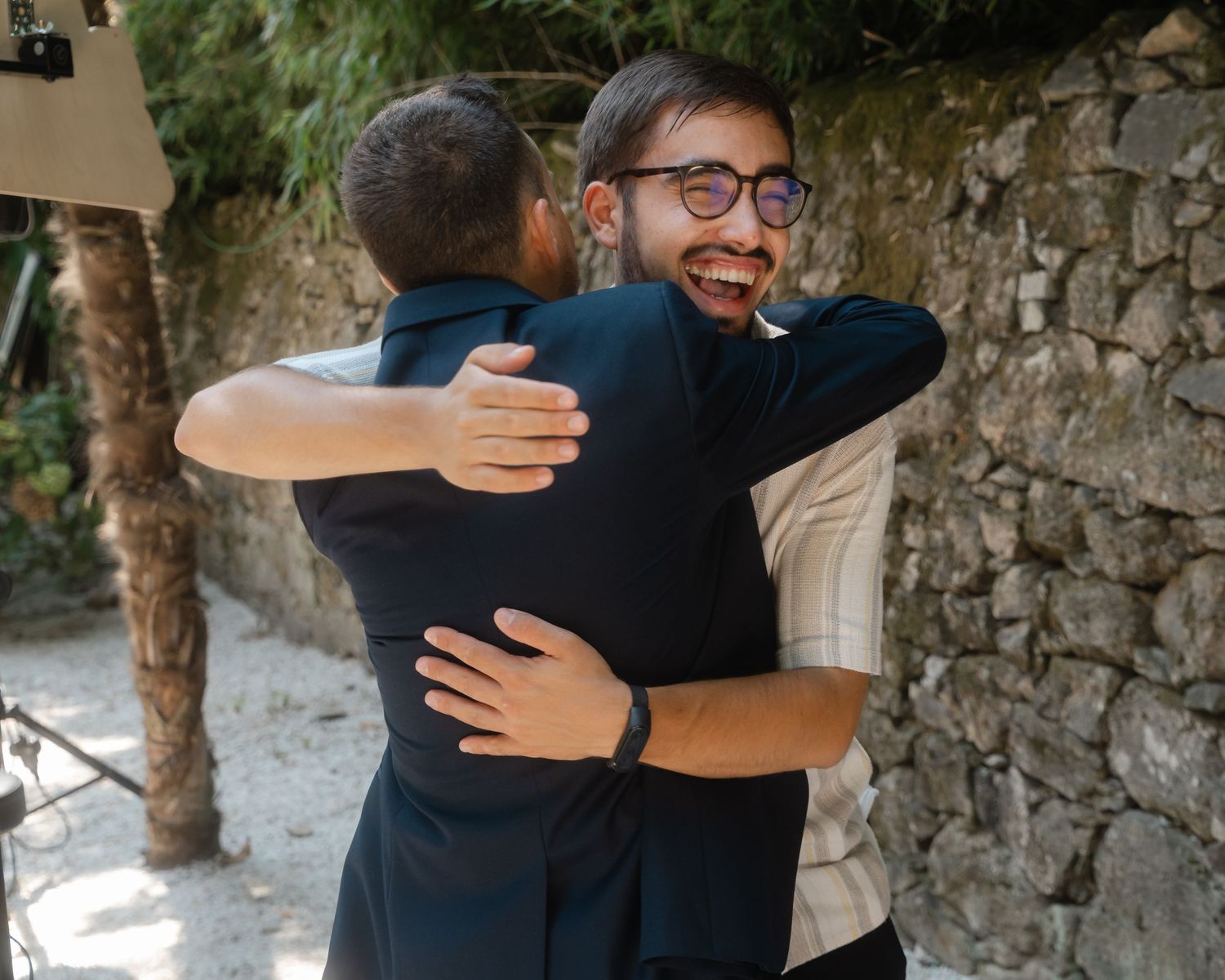 People sharing warm embraces and hugs against a stone wall backdrop.