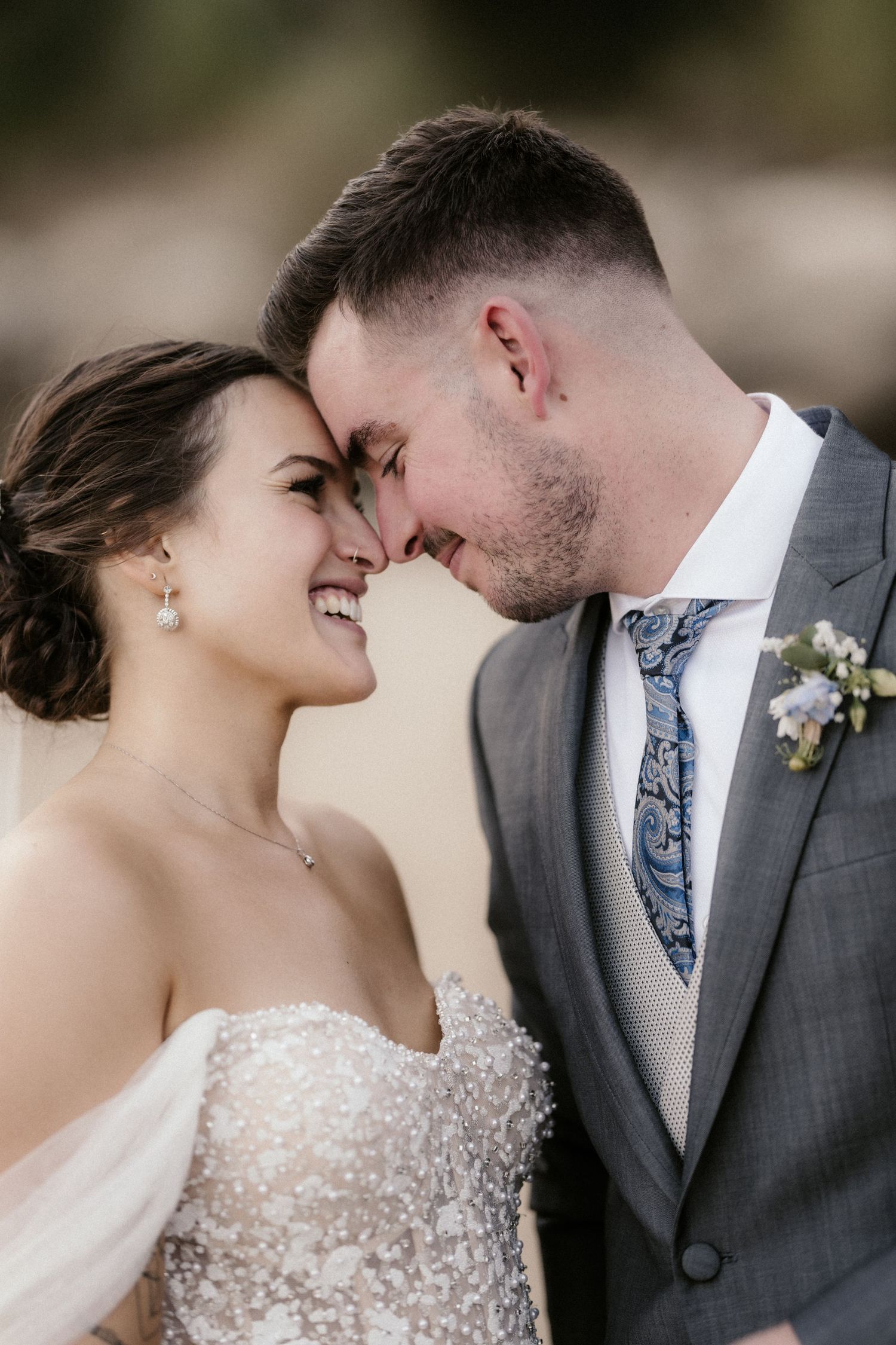 A romantic wedding portrait of a couple sharing an intimate forehead touch moment in formal attire.