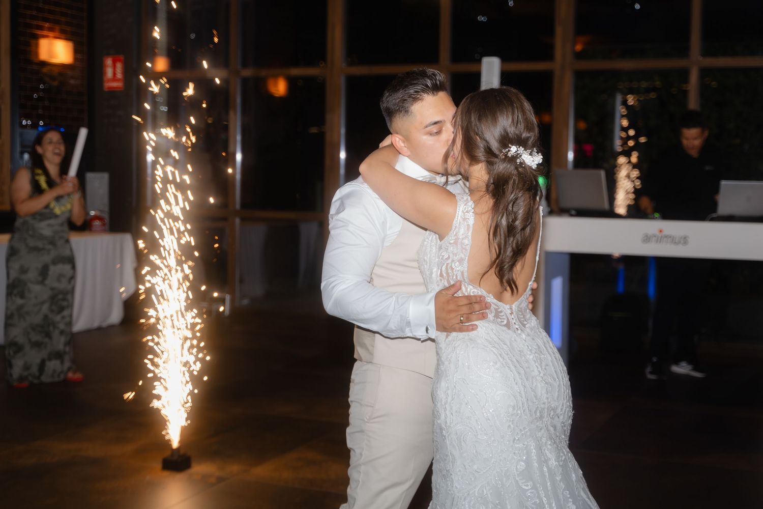 A couple shares their first dance at a wedding reception with sparklers glowing in the background.