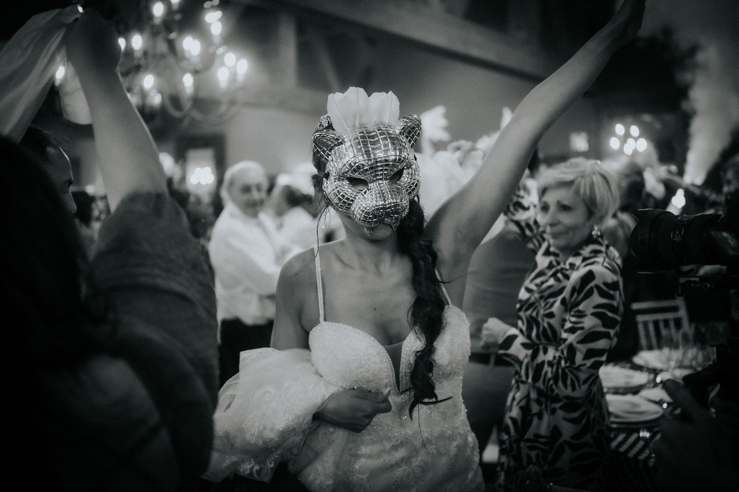 Black and white photo of a couple dancing at a wedding reception with guests watching in the background.