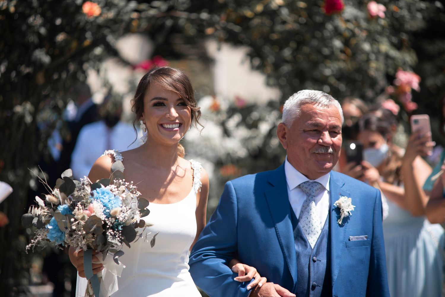 Wedding couple walks together during outdoor celebration with guests.