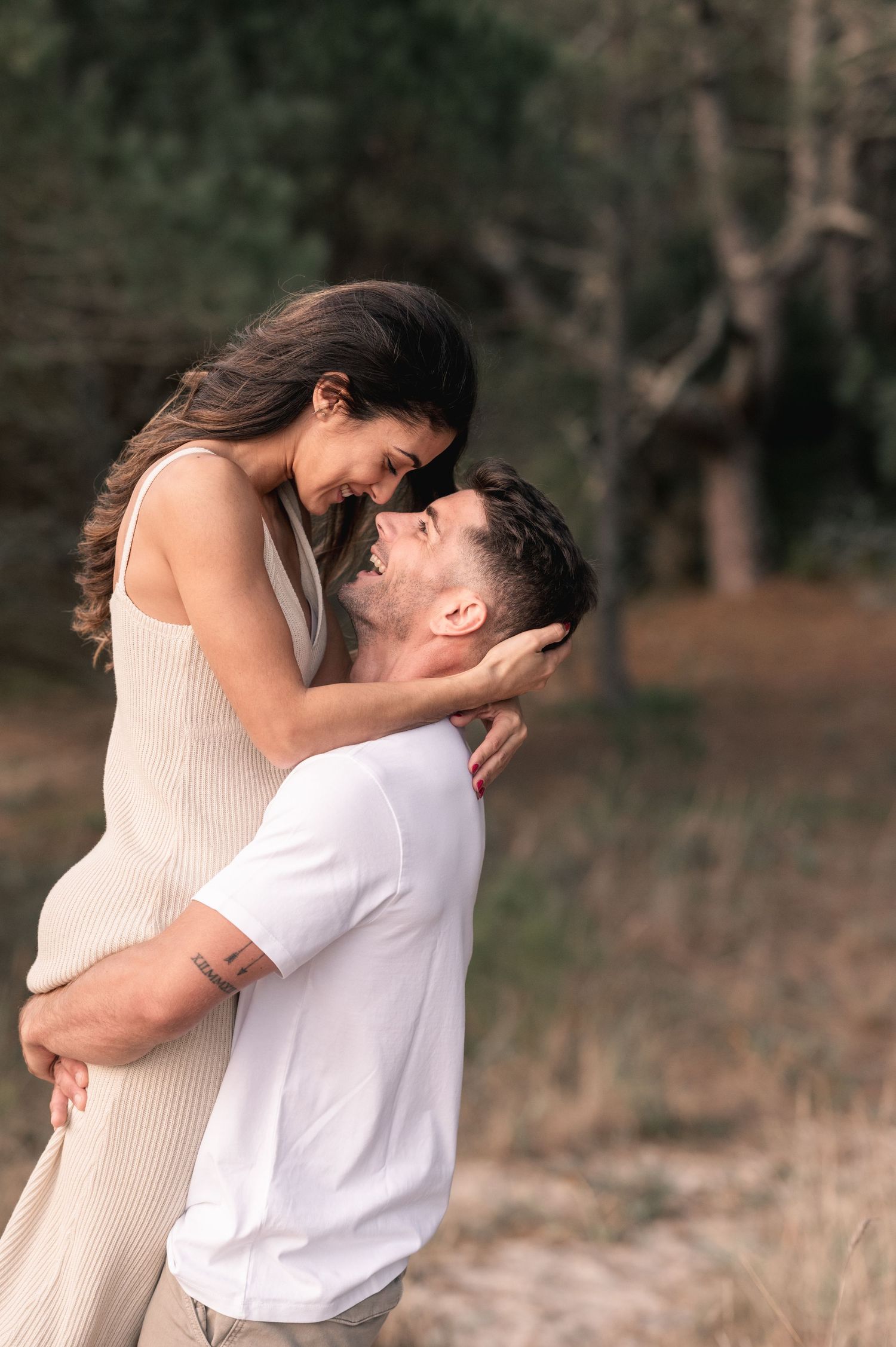 Couple shares intimate embraces and kisses in natural outdoor setting with soft lighting.