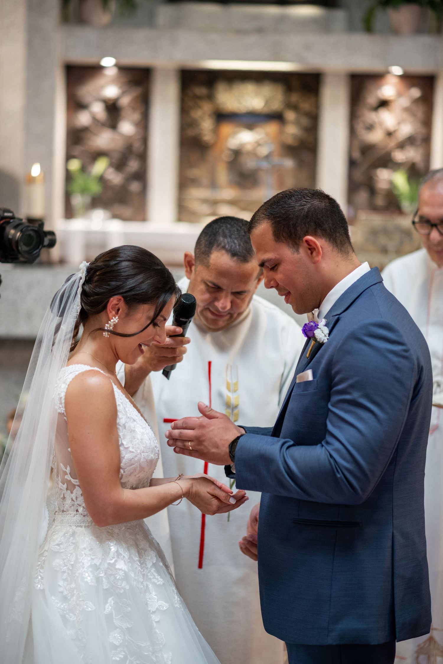 A couple exchanges rings during their wedding ceremony in an elegant indoor venue.