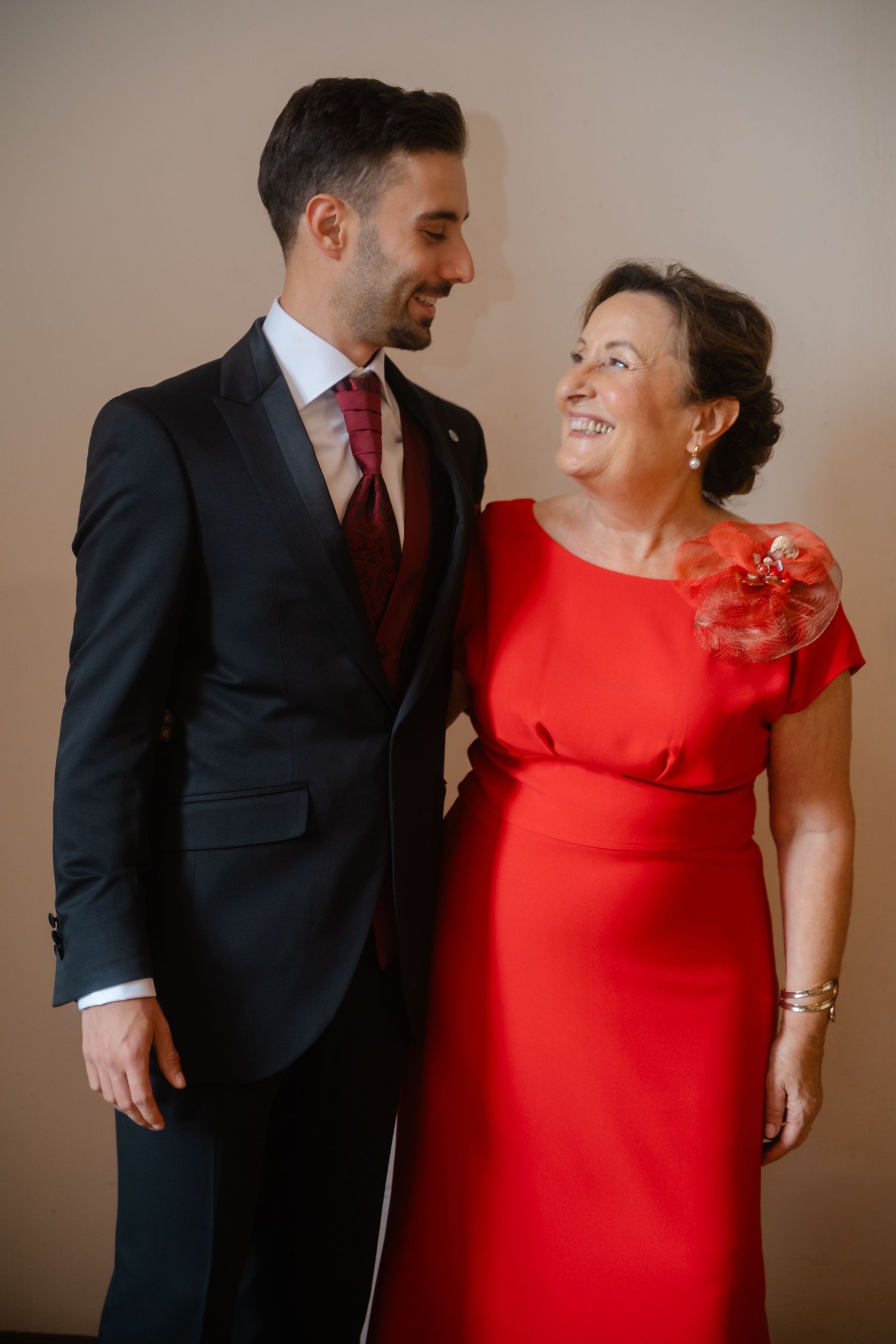 A couple in formal attire, with a red dress and dark suit, share candid laughing moments in a photo series.