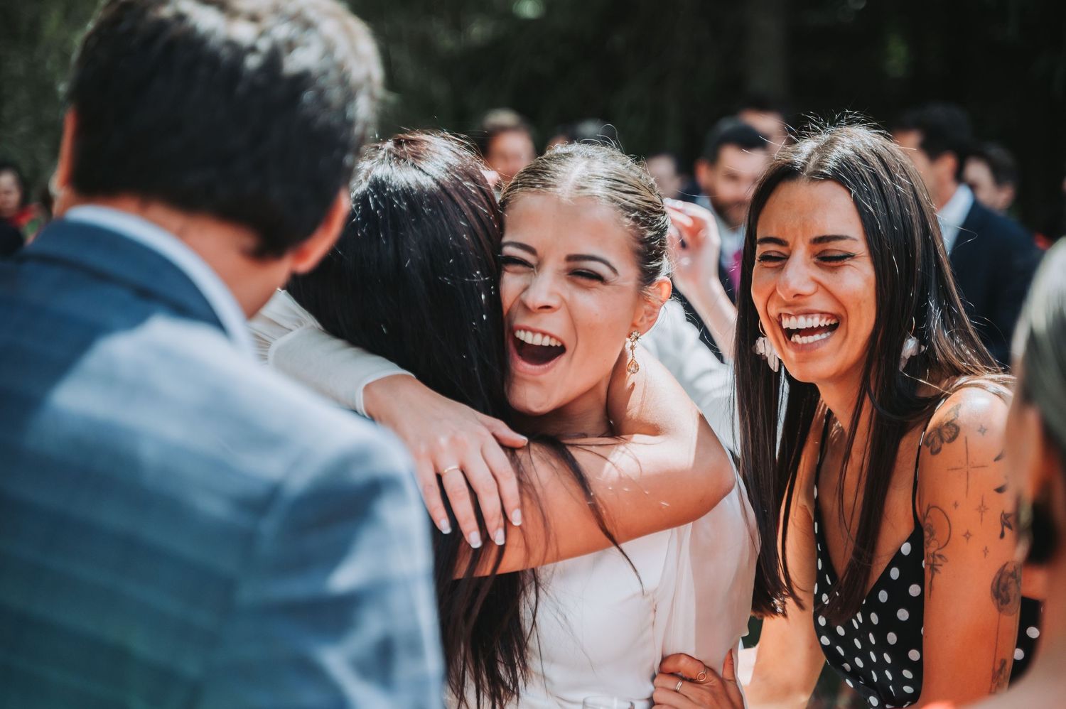 Wedding guests share joyful laughter and embraces during outdoor celebration.
