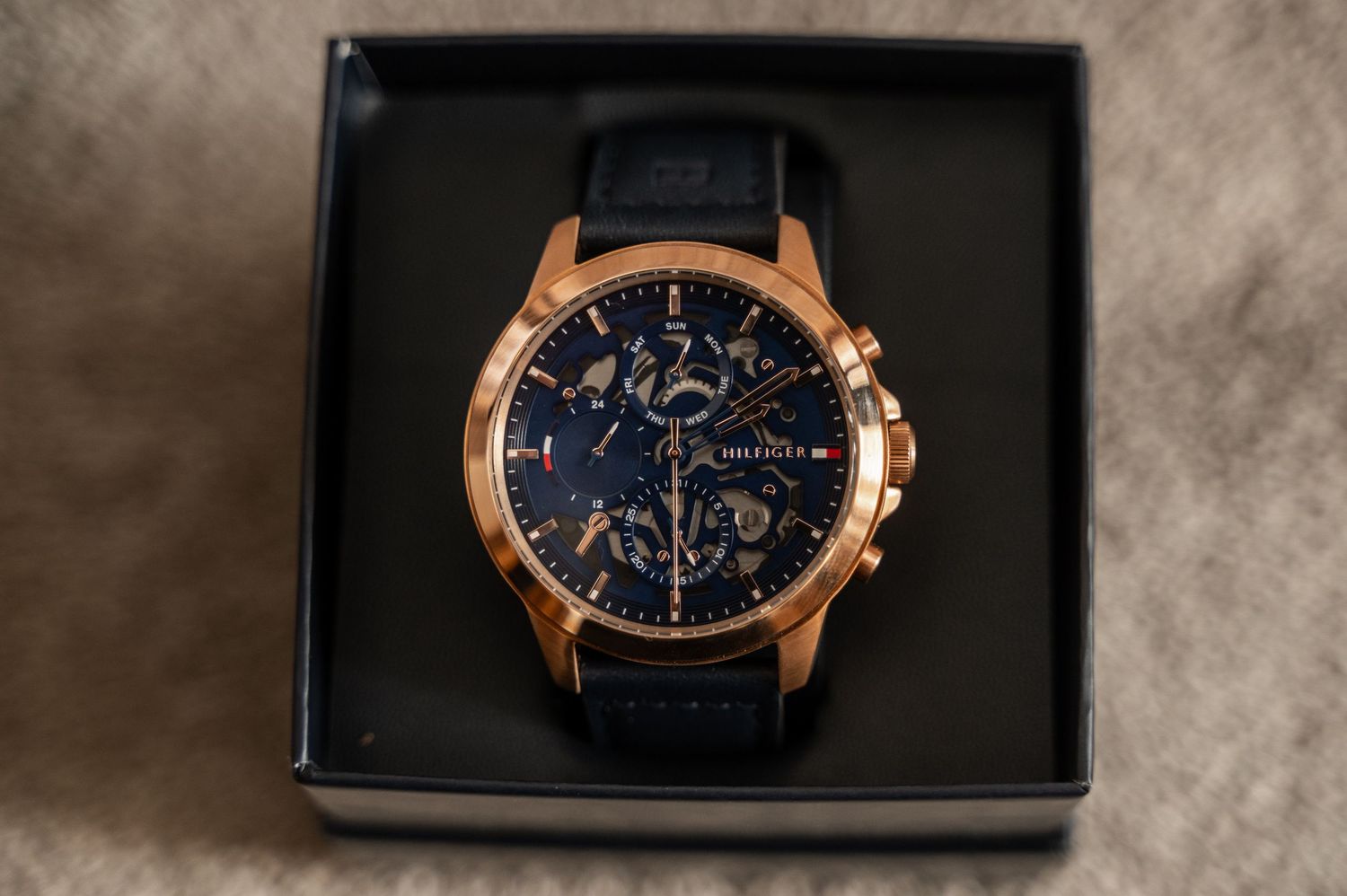 Luxury chronograph watch with rose gold case and navy blue dial shown from multiple angles in product photography.