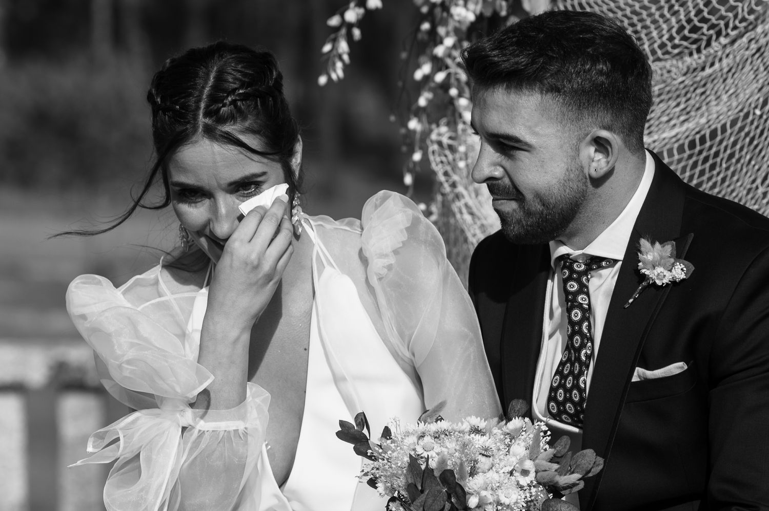 A couple shares a romantic kiss under a white umbrella during their wedding celebration.