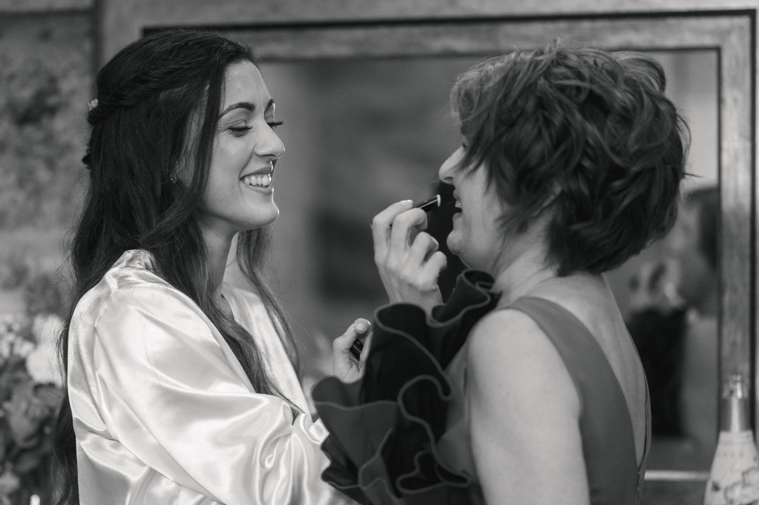A candid black and white moment of wedding day makeup preparation.