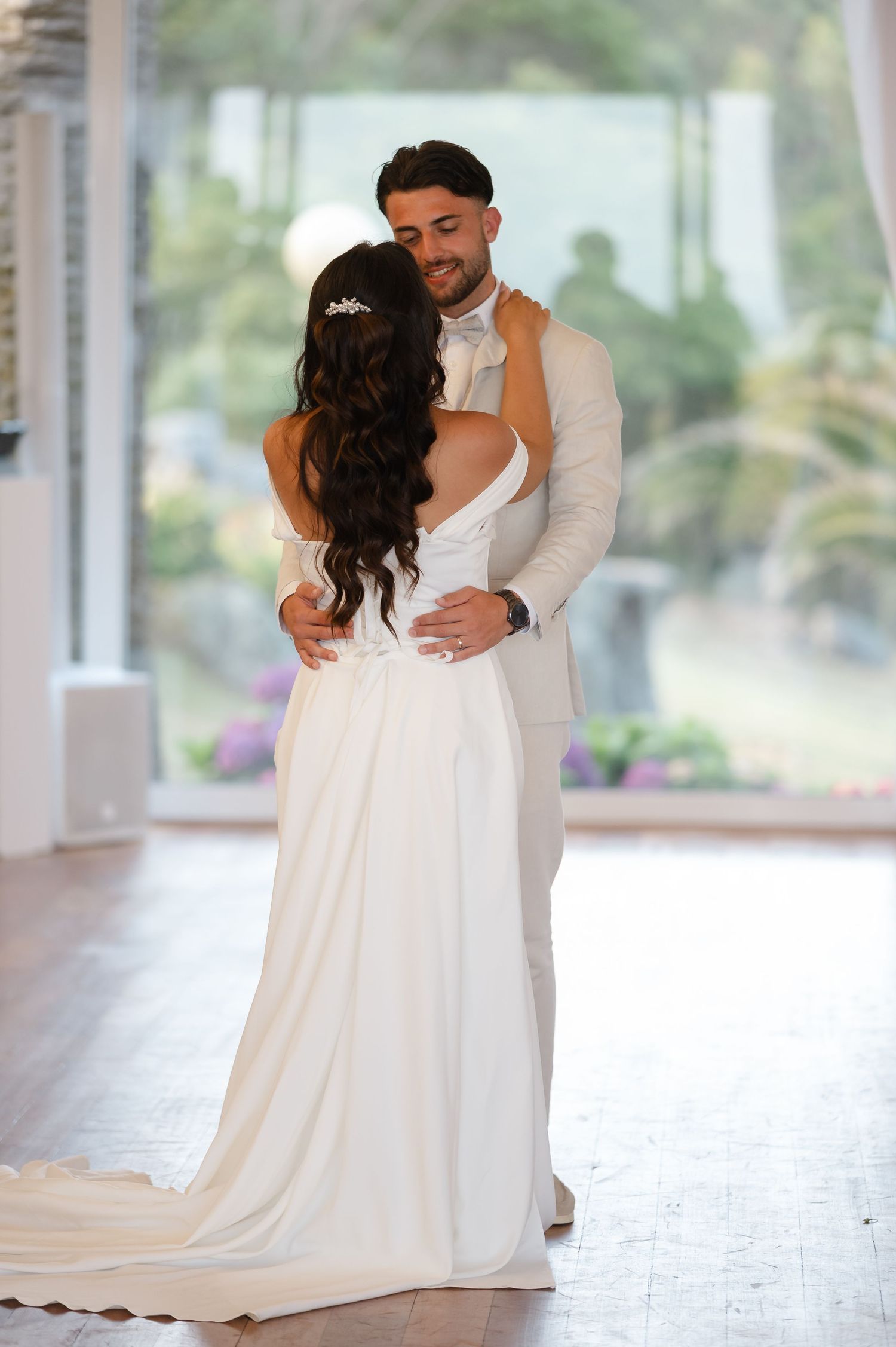 A couple shares an intimate moment during their first dance at an elegant wedding venue with natural lighting.
