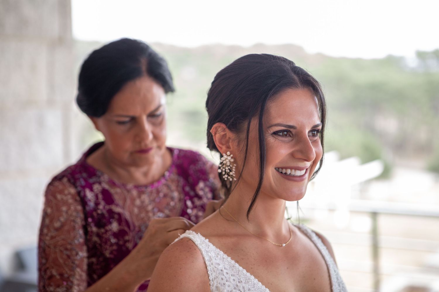 Candid moment of bridal preparation in natural window light.