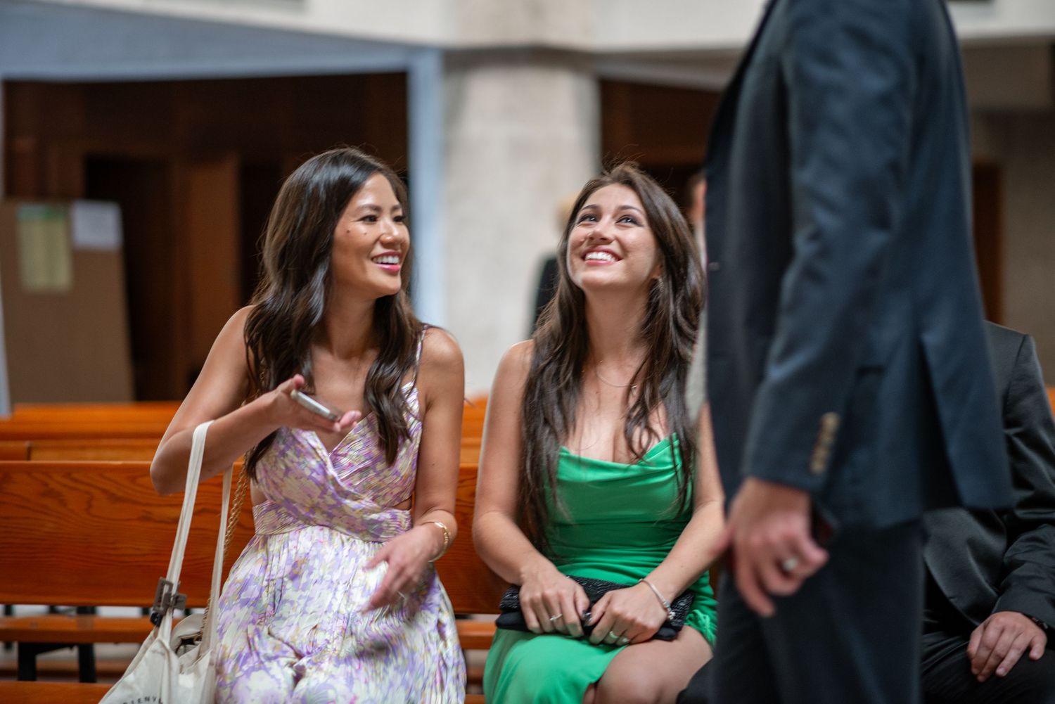A group of people sitting together at a church pew, wearing formal attire and smiling during a special occasion.