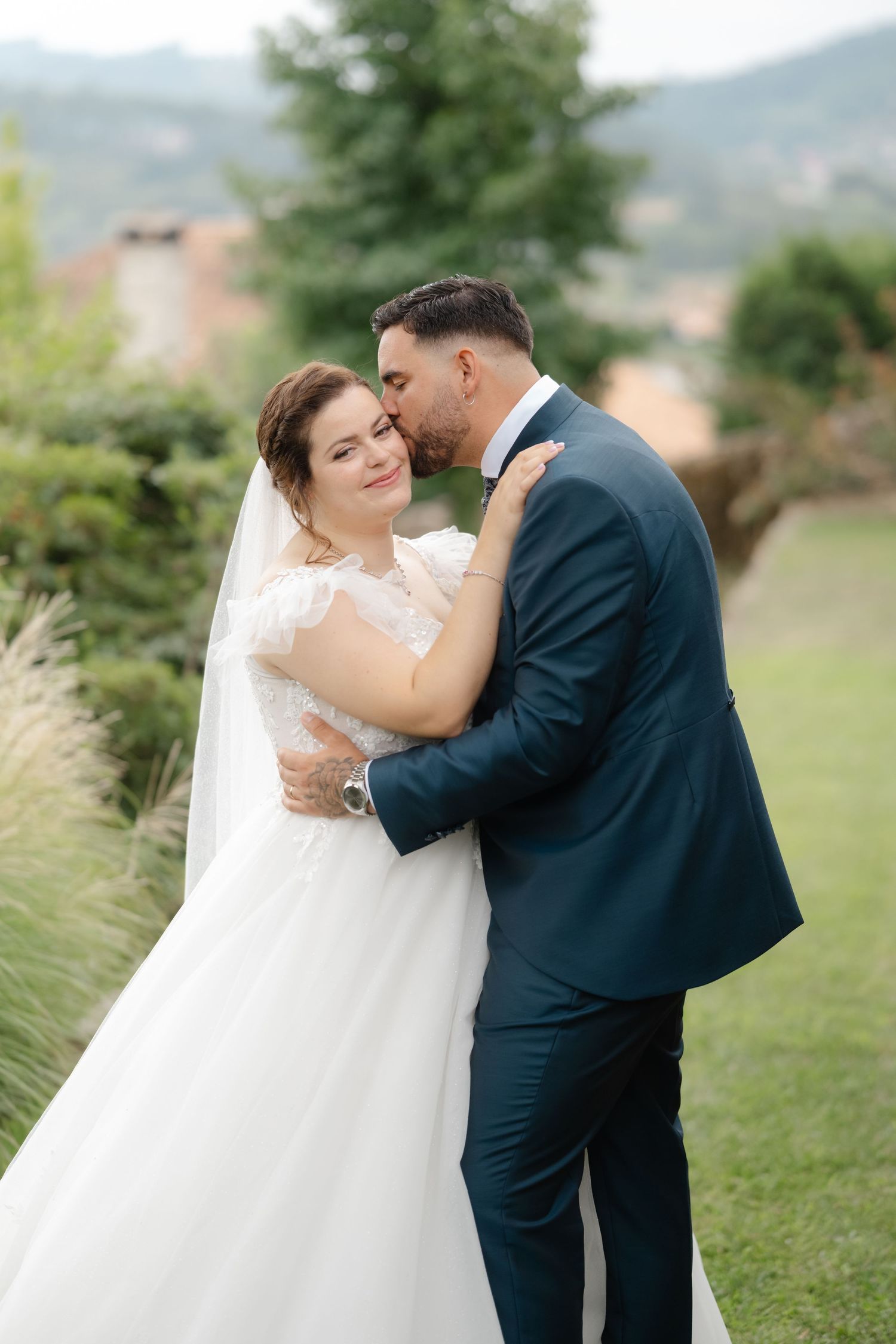 A couple shares an intimate moment during their outdoor wedding photoshoot in a scenic mountain setting.