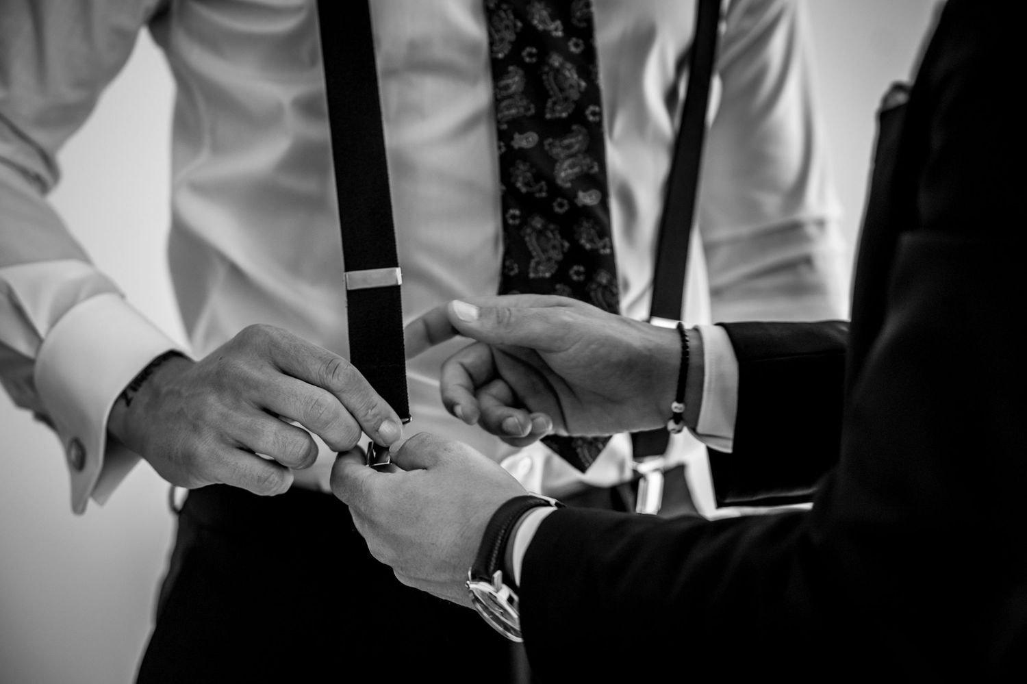 Close-up shot of hands adjusting a black bowtie against a white dress shirt.