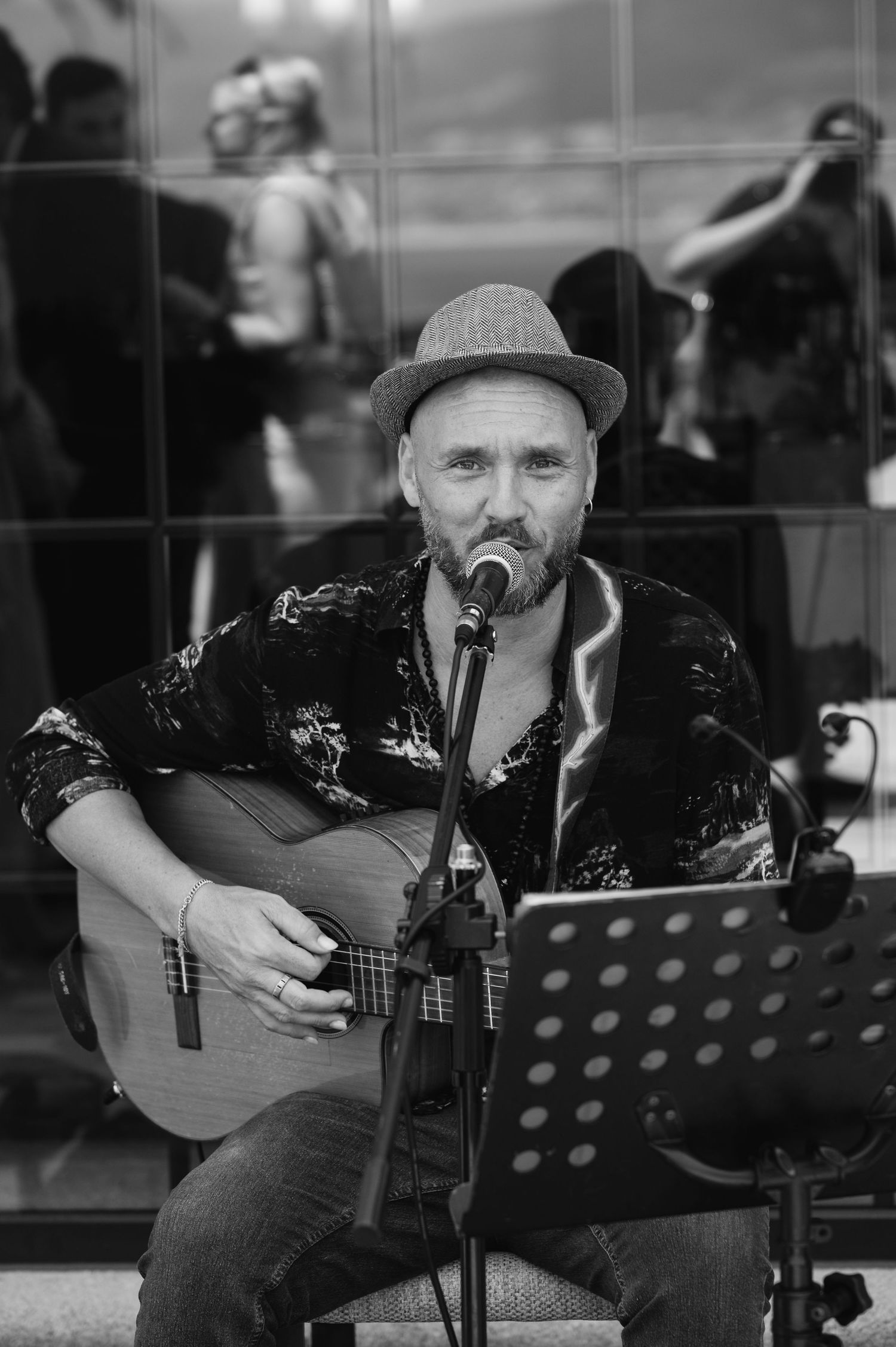 Black and white photos show a musician performing with an acoustic guitar and music stand in an intimate setting.